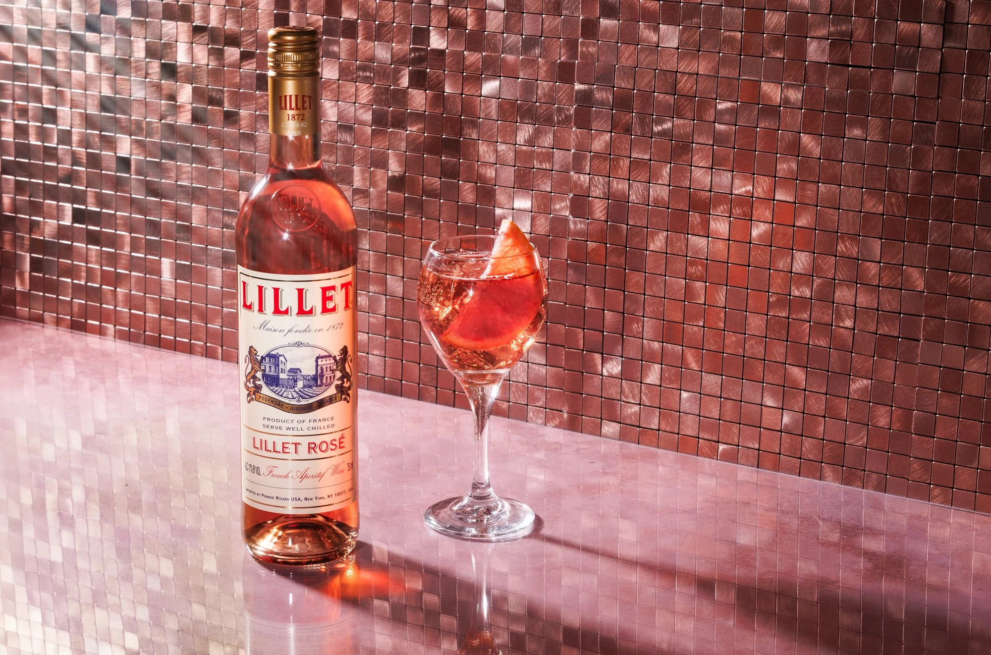 Commercial beverage photo of a Lillet rose' bottle with a glass and grapefruit slice for an advertising campaign.