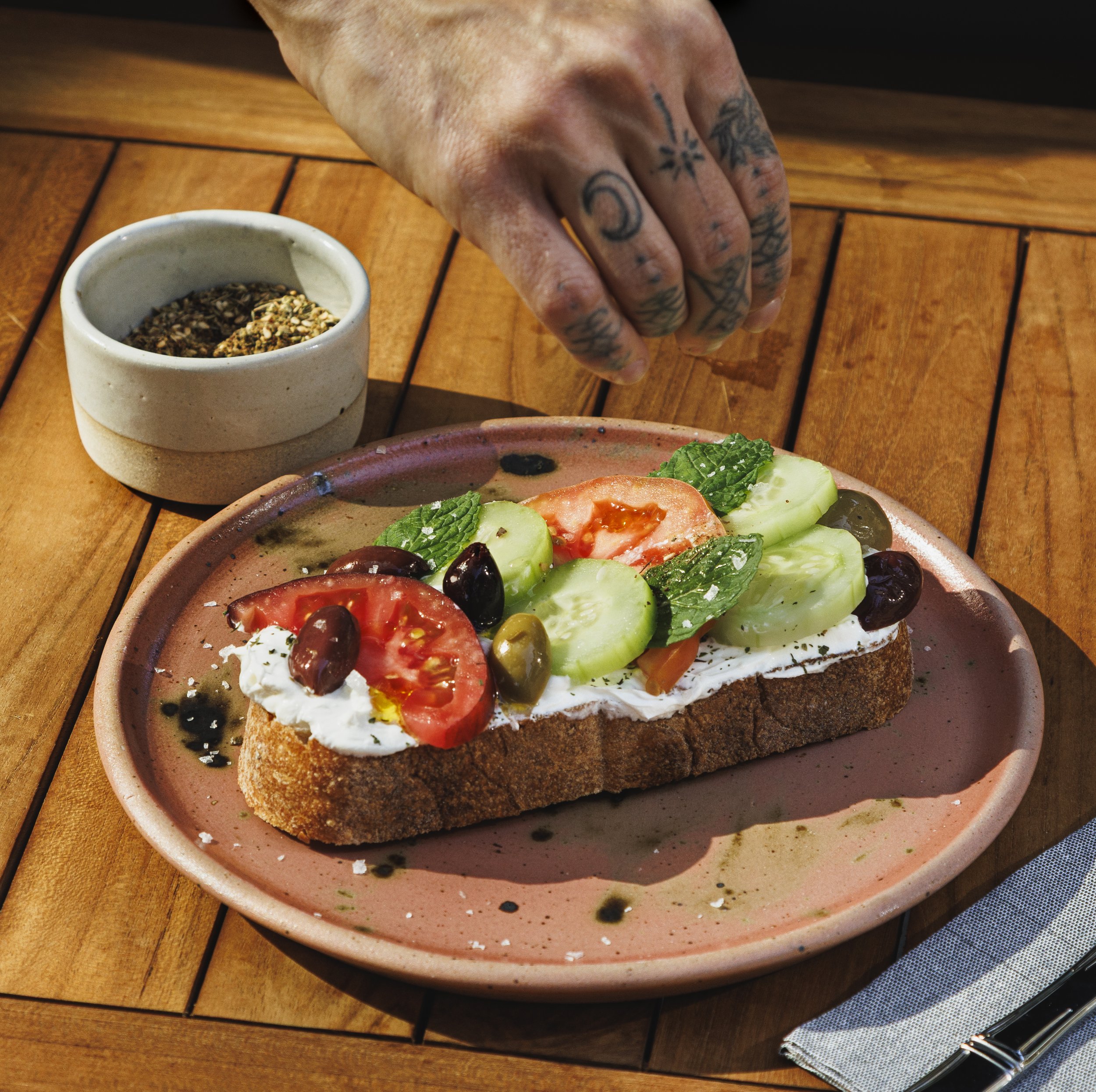 Commercial food advertising photo of a hand sprinkling spices on a dish.
