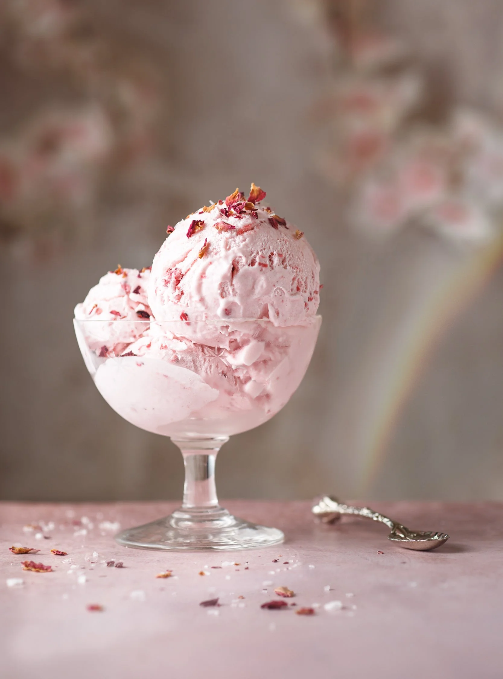 Editorial food photo of strawberry ice cream with rose petals and a rainbow for dairy ad campaign.