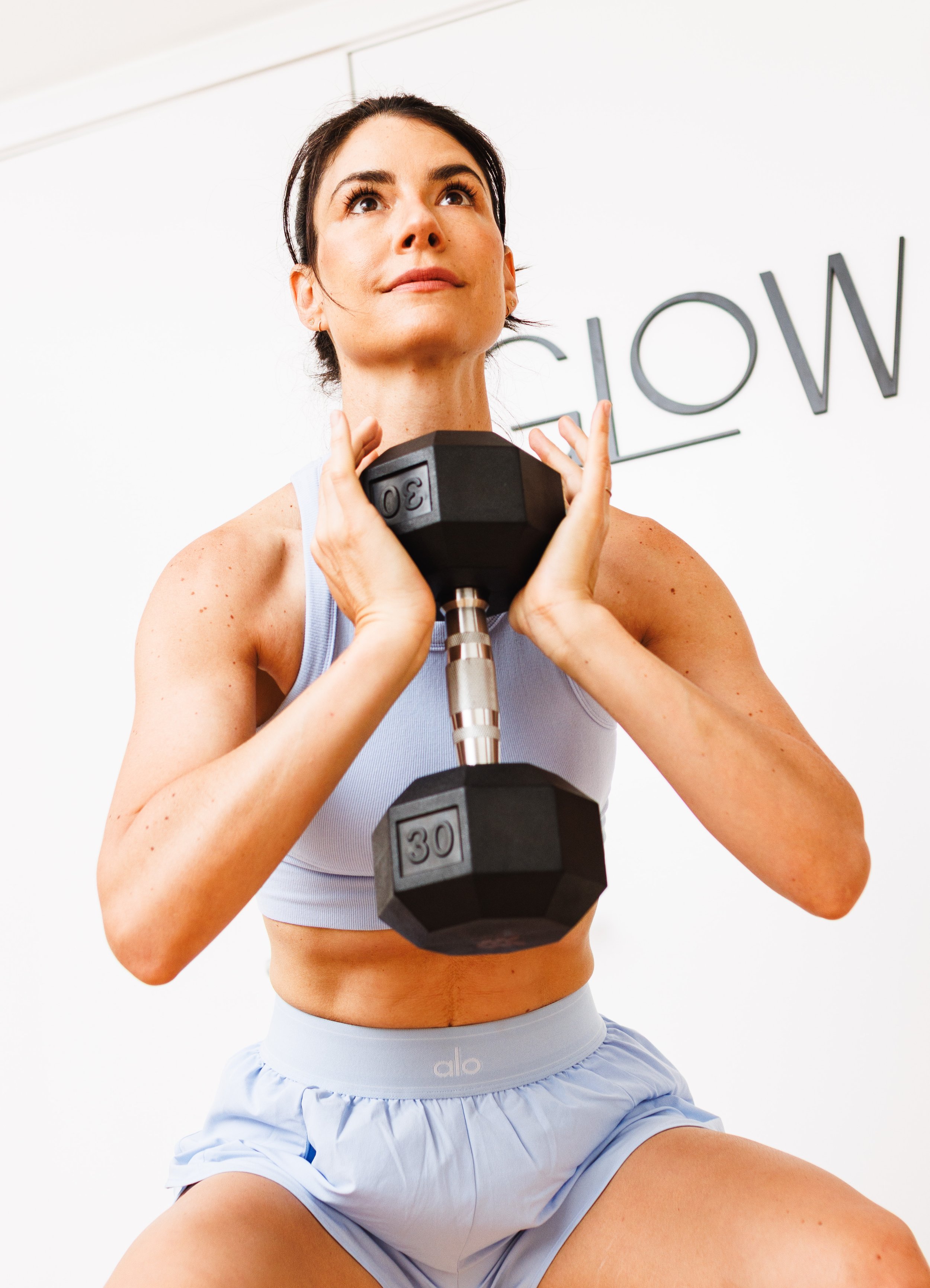 Commercial lifestyle photo of a woman lifting weights for a fitness apparel advertising campaign.
