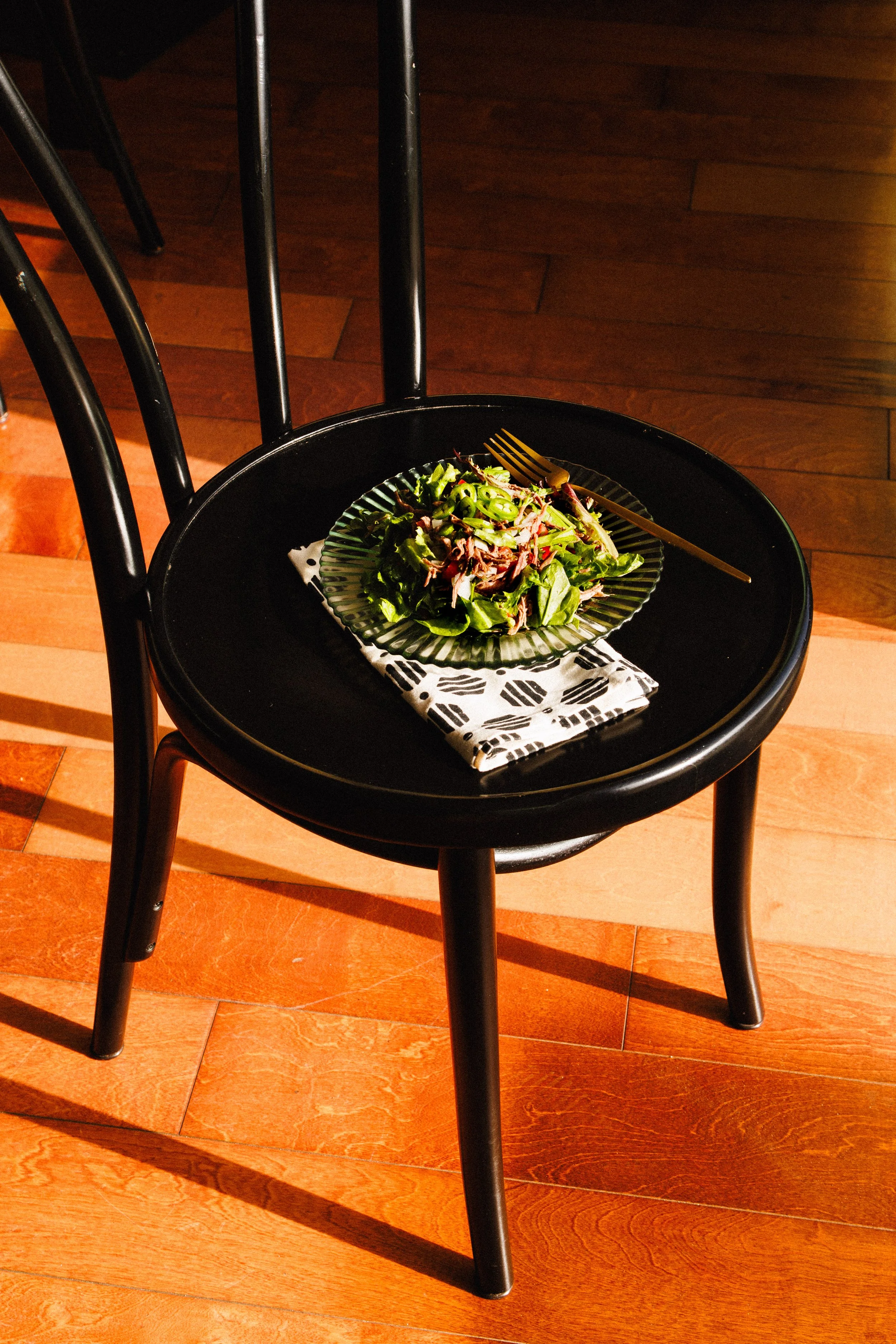 Editorial interiors photo of a chair with a plate of food on it and dramatic shadows.