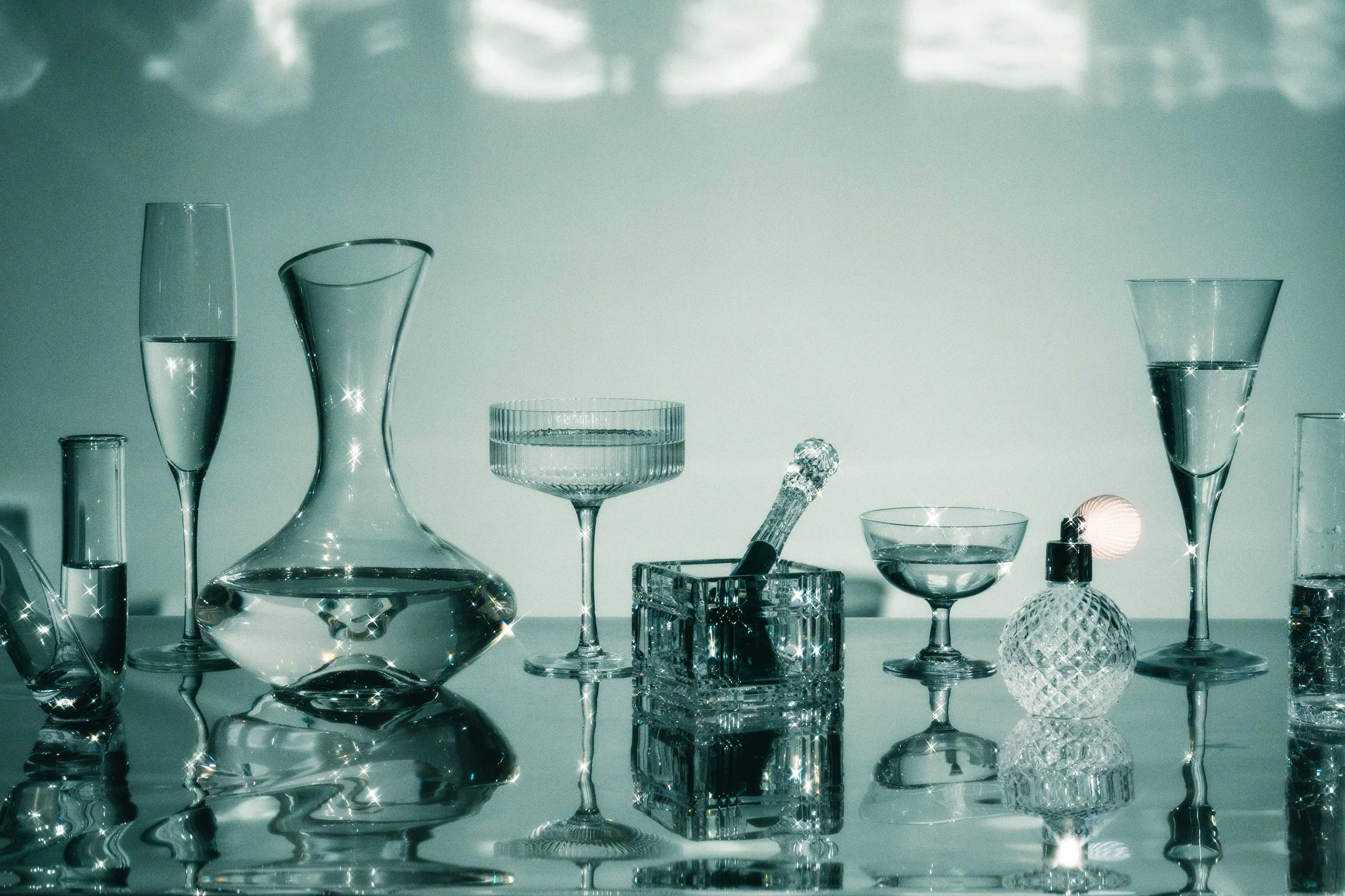 Conceptual still life photo of glassware arranged in a row, filled with sparkling liquids.