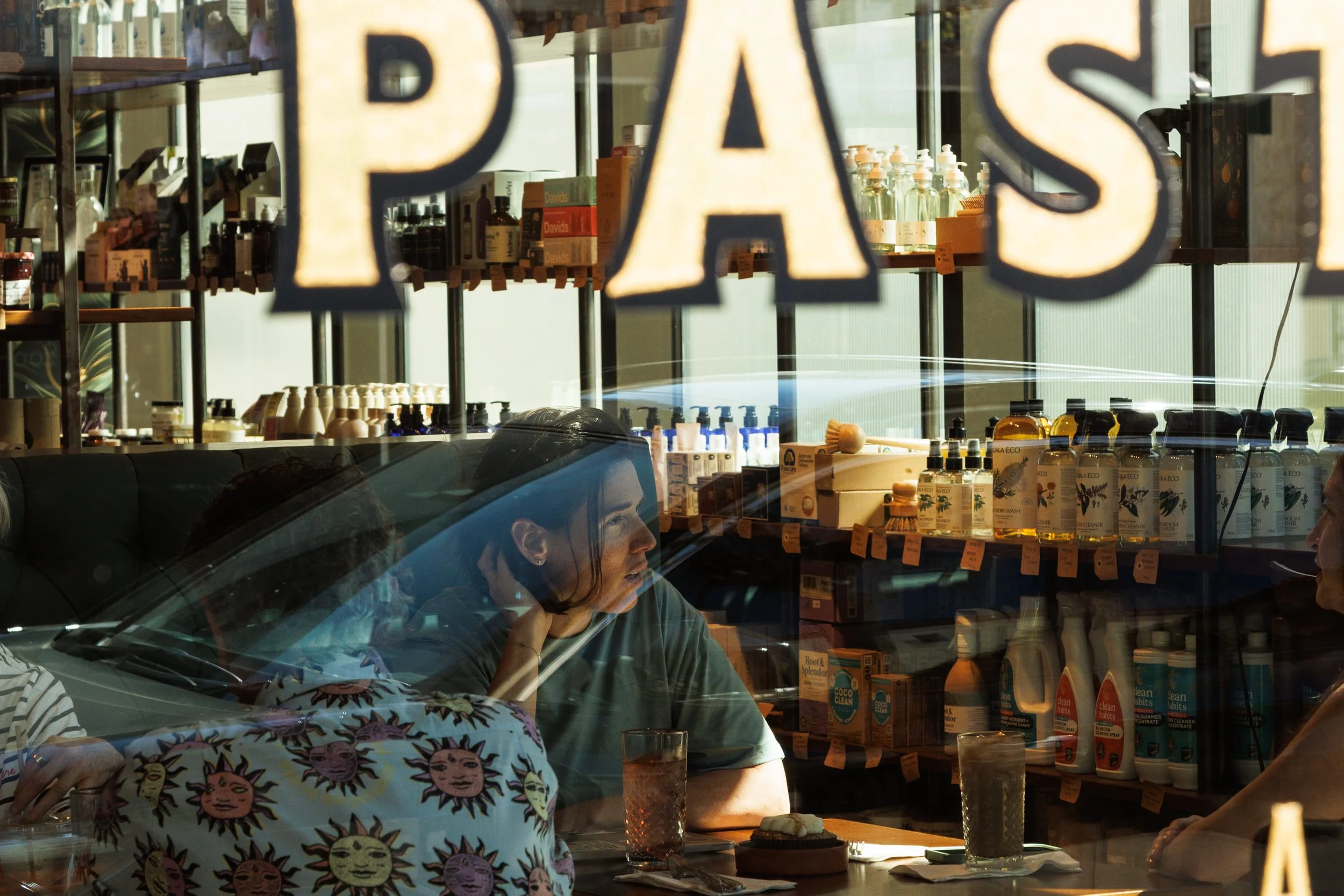 Commercial lifestyle photo of people talking inside a cafe with reflections in the window, for a branded hospitality campaign.