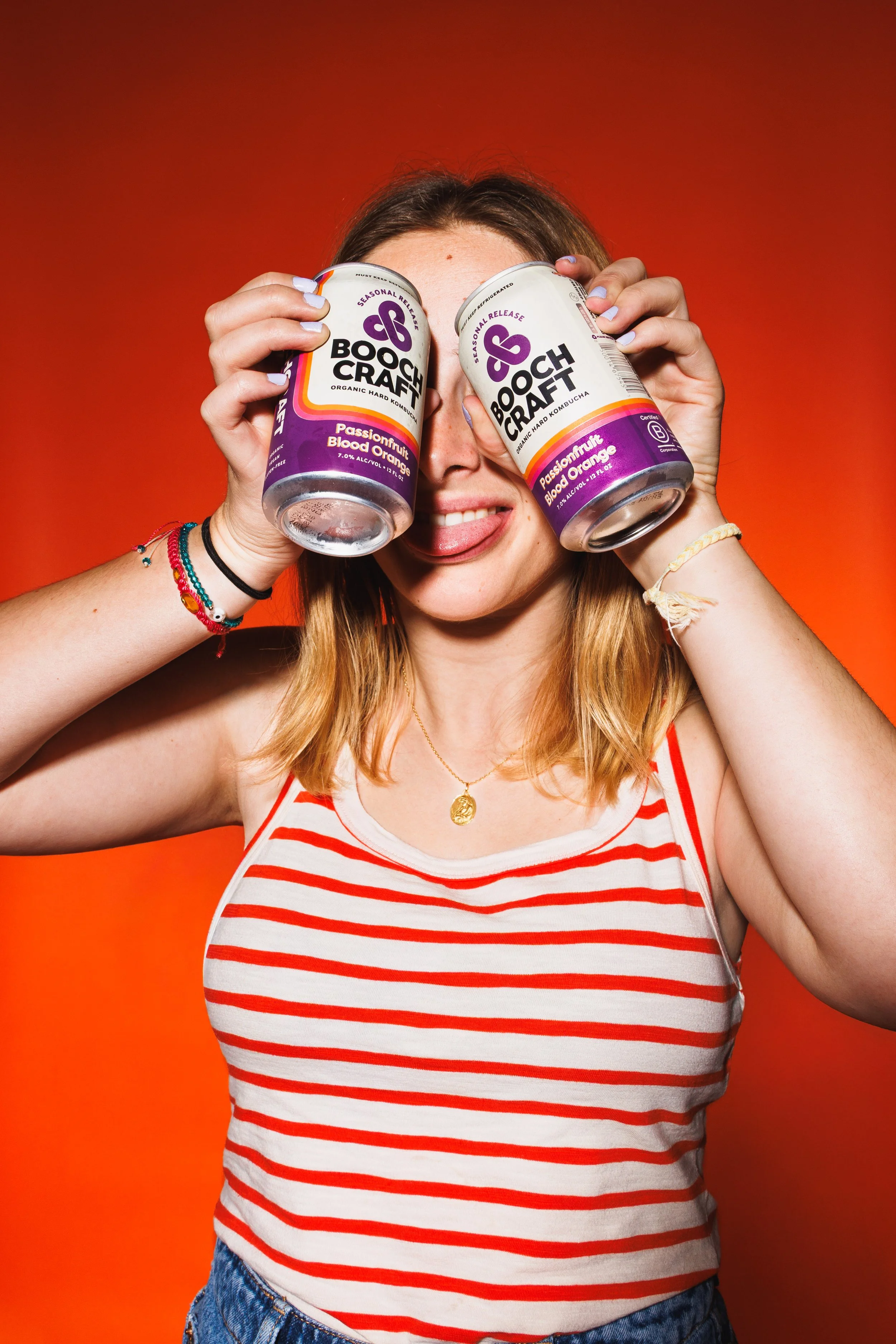 Commercial lifestyle photo for a canned beverage advertising campaign featuring a girl holding cans by her face.