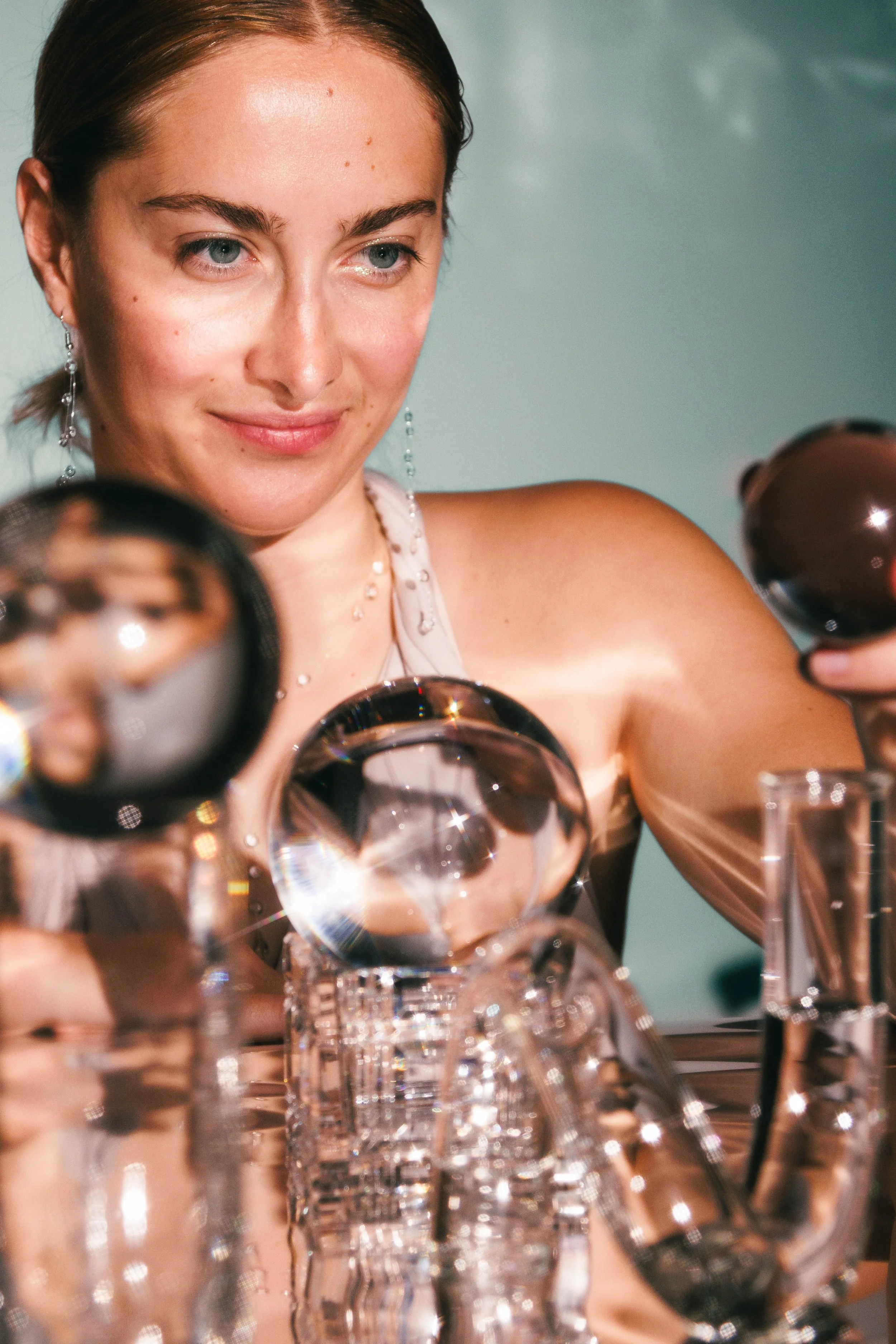 Editorial beauty photo of a woman playing with crystal balls and glass.