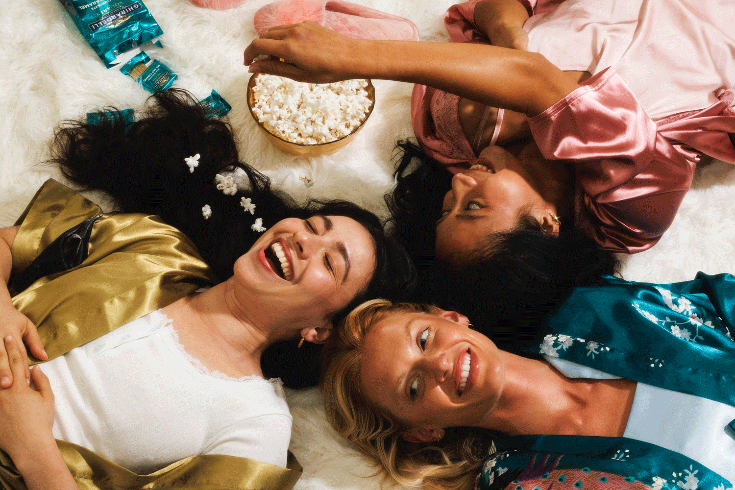Commercial lifestyle GIF of woman throwing popcorn into their mouths at a slumber party.