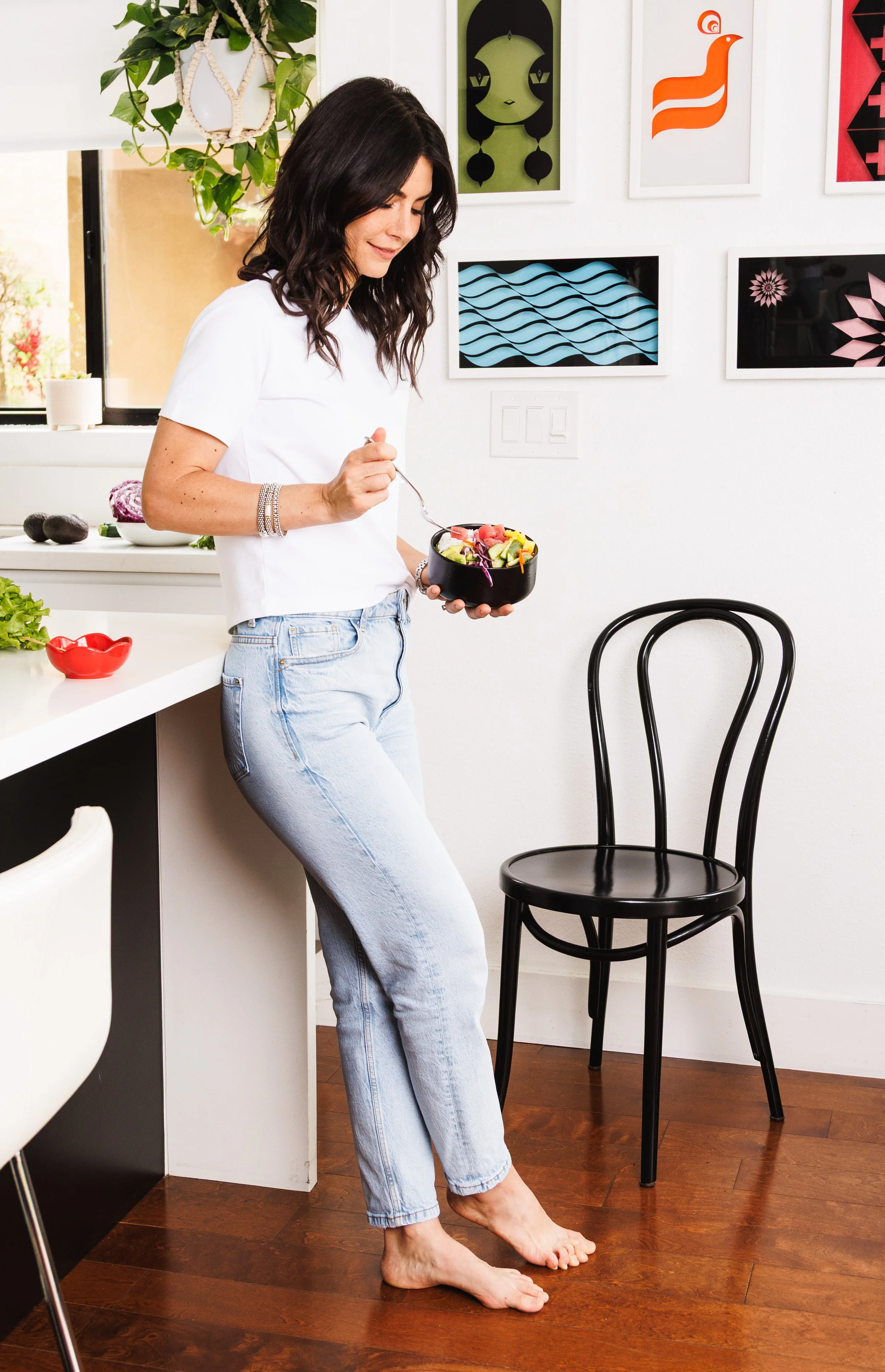 Commercial lifestyle photo of a wellness coach eating a healthy poke bowl barefoot in her kitchen in San Diego. Shot for her cookbook, by Amy Carson.