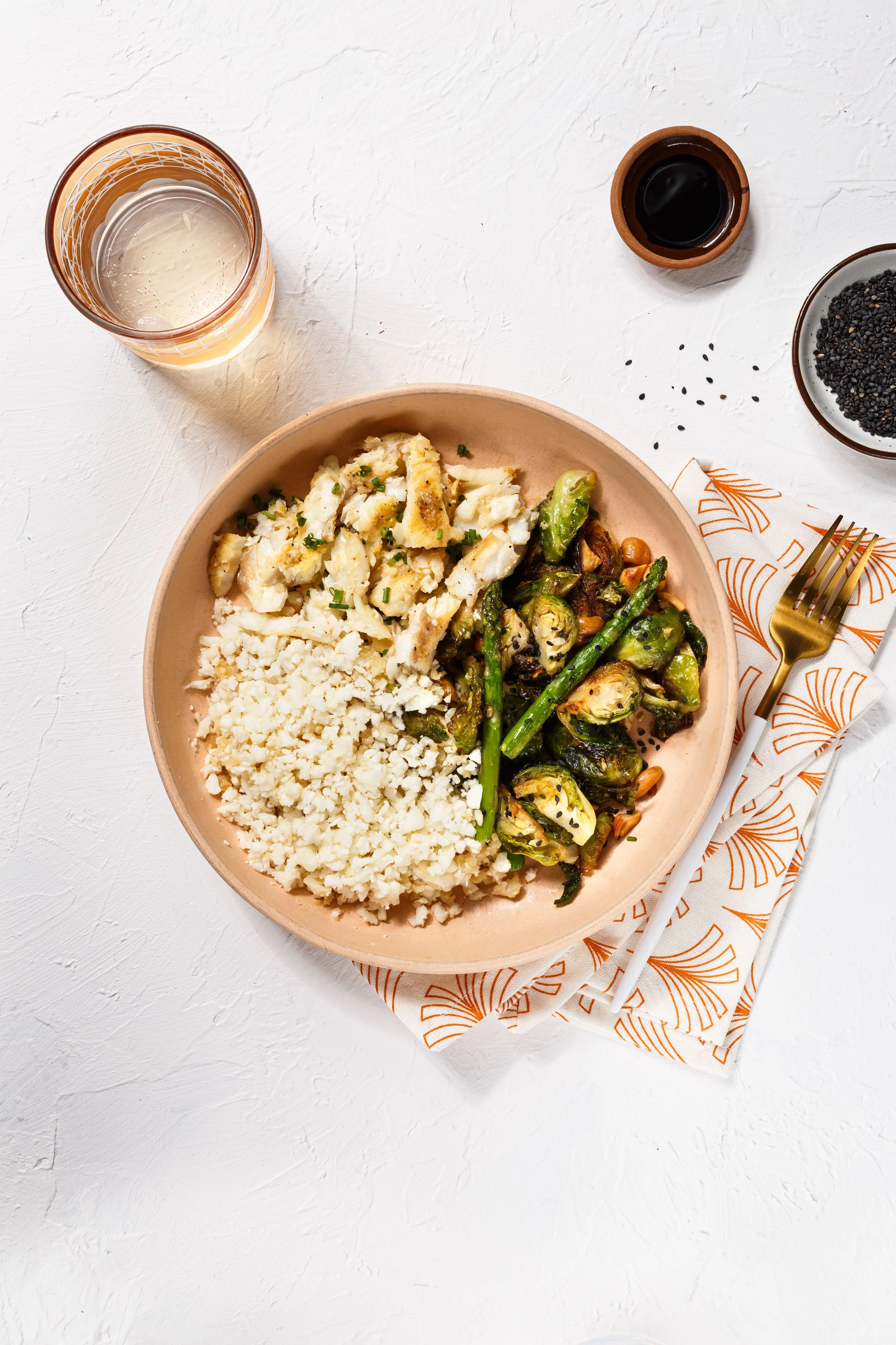 Commercial food photo of a healthy fish and veggie bowl on a white plaster surface for a brand campaign.