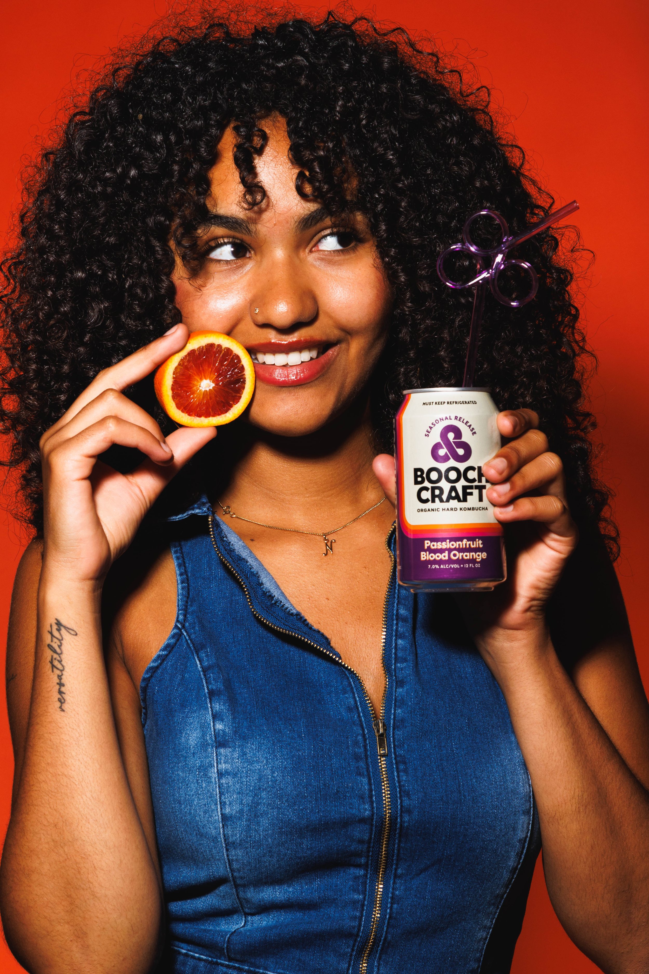 Commercial lifestyle portrait of a young women holding a can of Boochcraft and an orange for an advertisement.