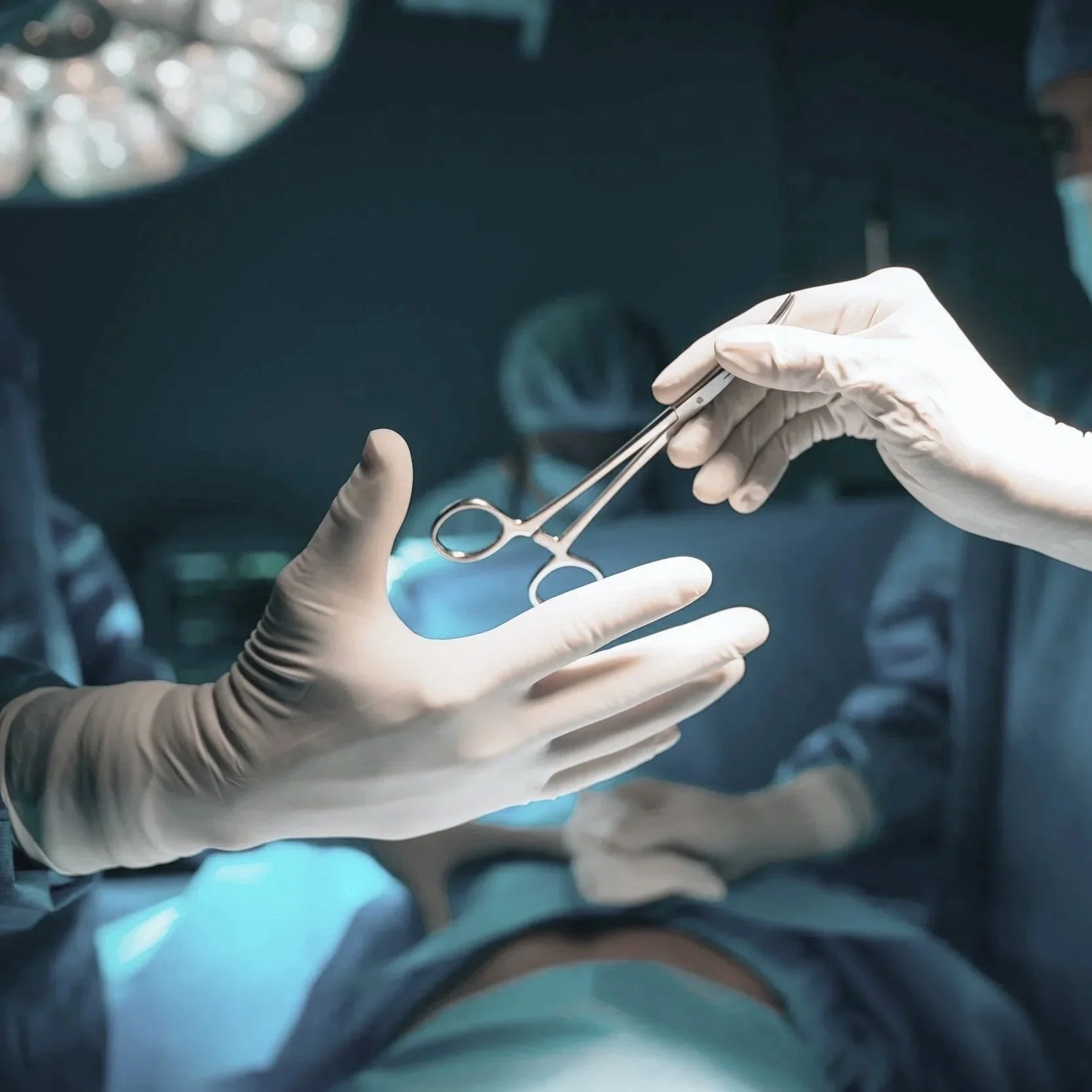 Close-up of a surgeon's gloved hands holding surgical forceps in an operating room with bright lights.