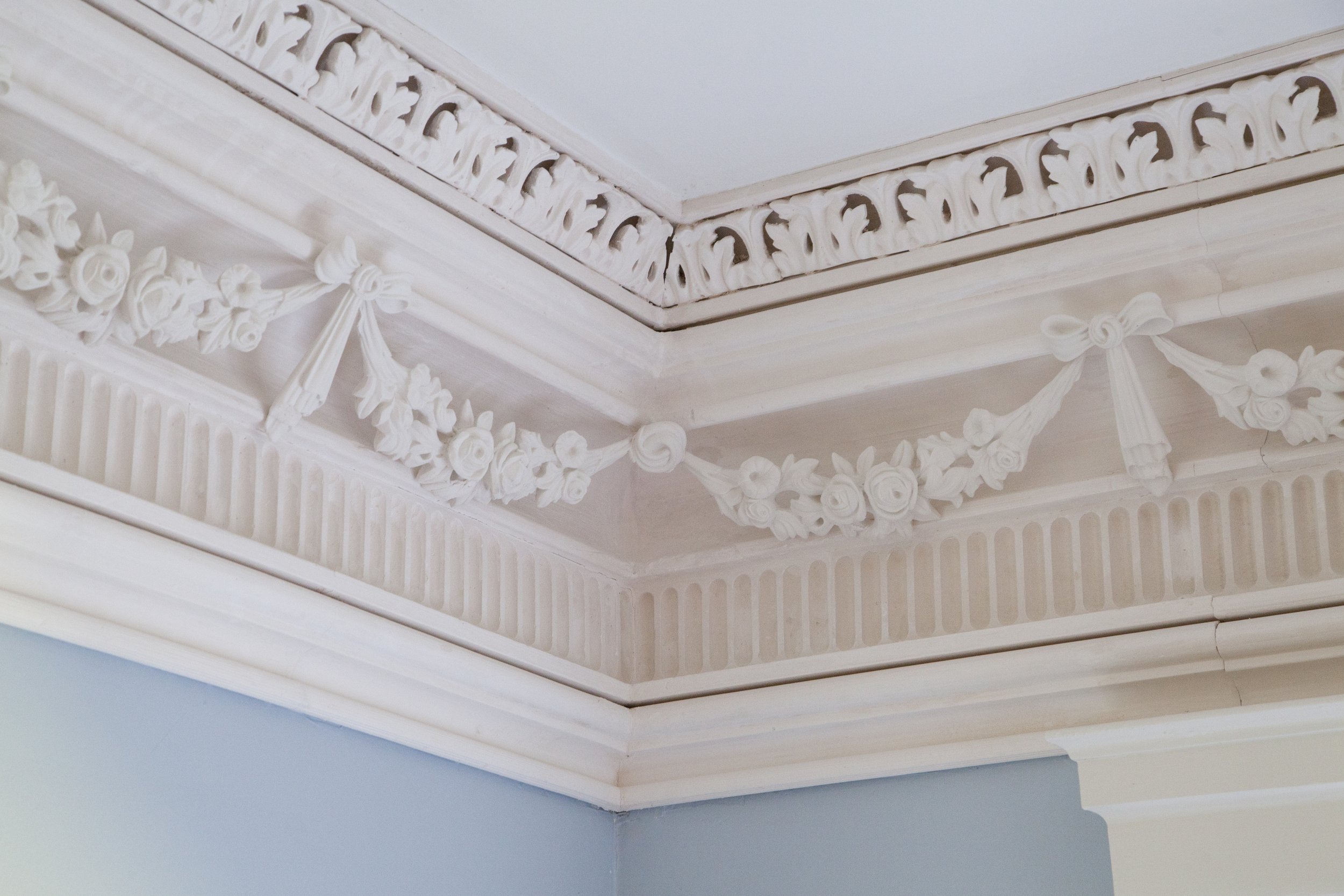 Glen Mary Plantation plaster restoration of interior ceiling corner with ornate white molding and decorative trim.