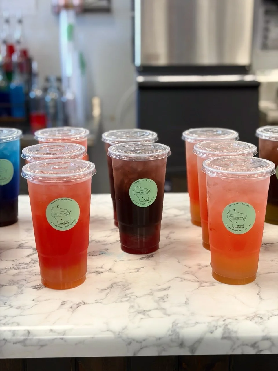 Multiple cups of tea with different colors on a marble counter at a tea shop.