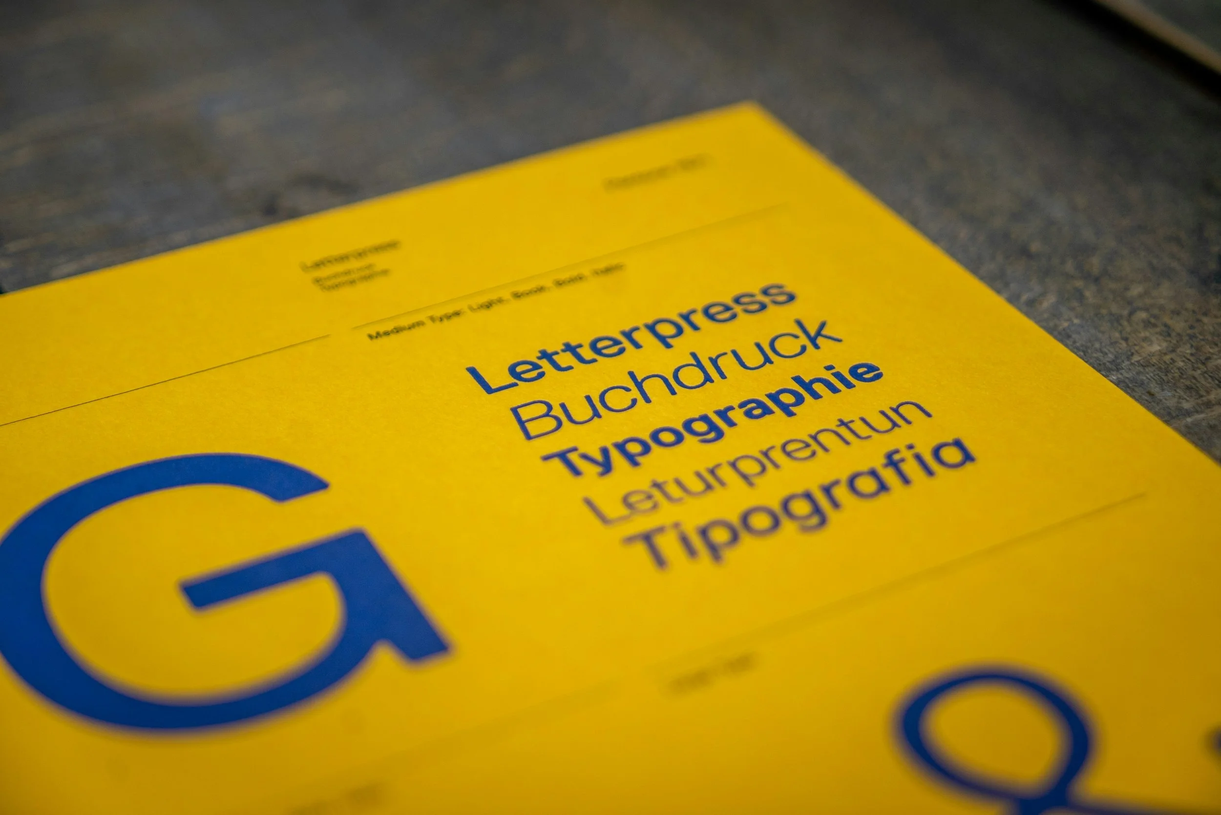 Close-up of a yellow sheet of paper with blue and black printed text, on a dark surface.