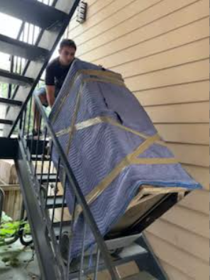 Professional mover carrying protected furniture upstairs during a residential move in Austin, TX.