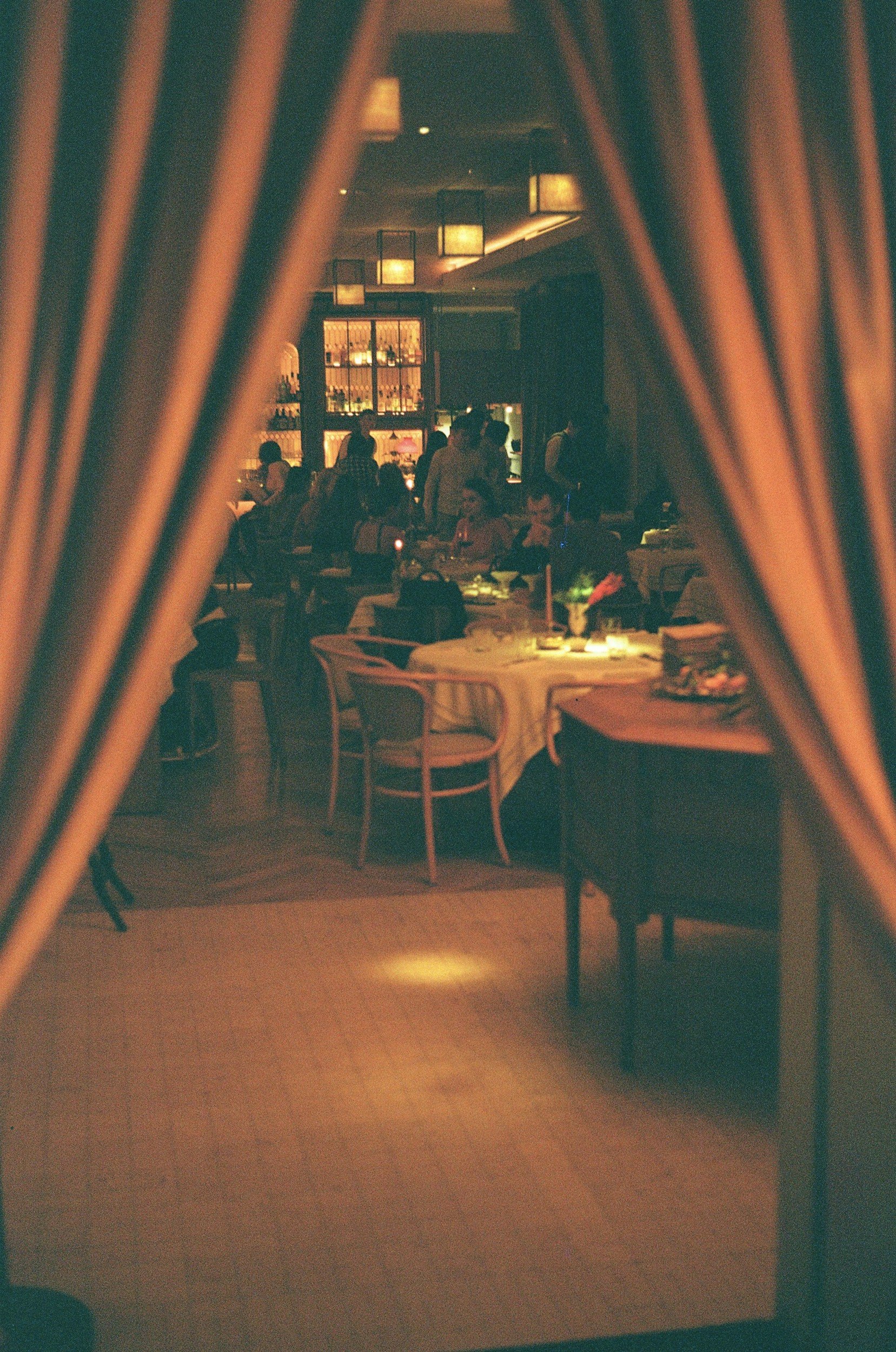 A warm, candlelit peek behind the curtain of a shared dining table at a local restaurant, showing hands clinking wine glasses over platters of artisanal canapés during a DCSC evening gathering.
