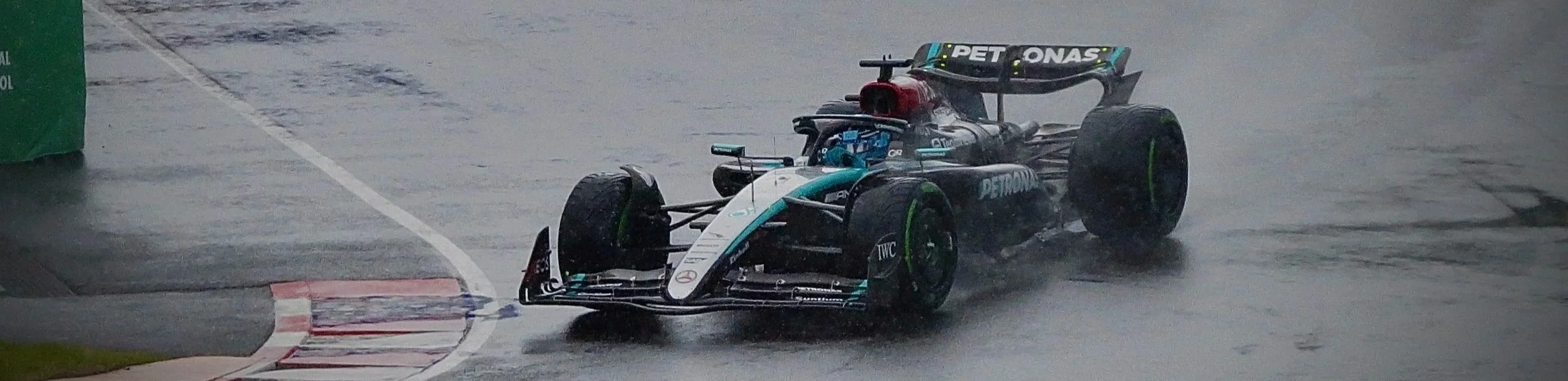 A Formula 1 car racing on a wet track in rainy conditions.