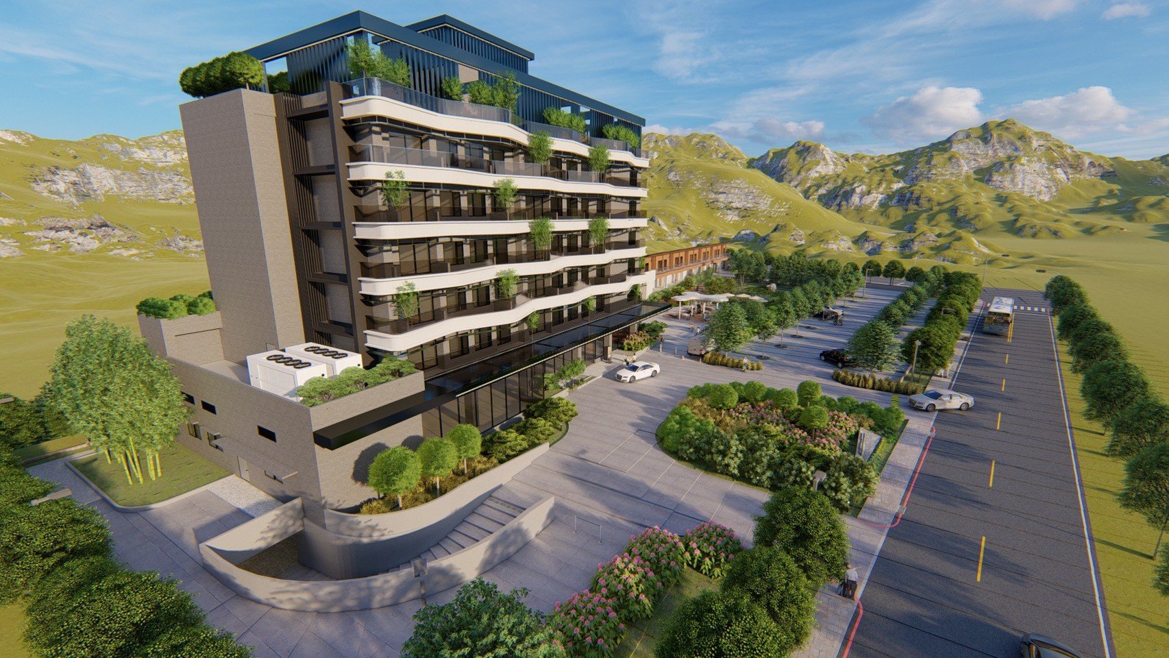 A modern multi-story building with balconies and green rooftop gardens is situated in a scenic mountainous area. The building features glass windows, a parking lot with cars, and surrounding landscaped greenery, with hills and mountains in the background.