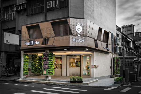 Exterior of a storefront for Fine Herbs, displaying green plants and purple flowers, with signage in English and Chinese, in an urban setting.