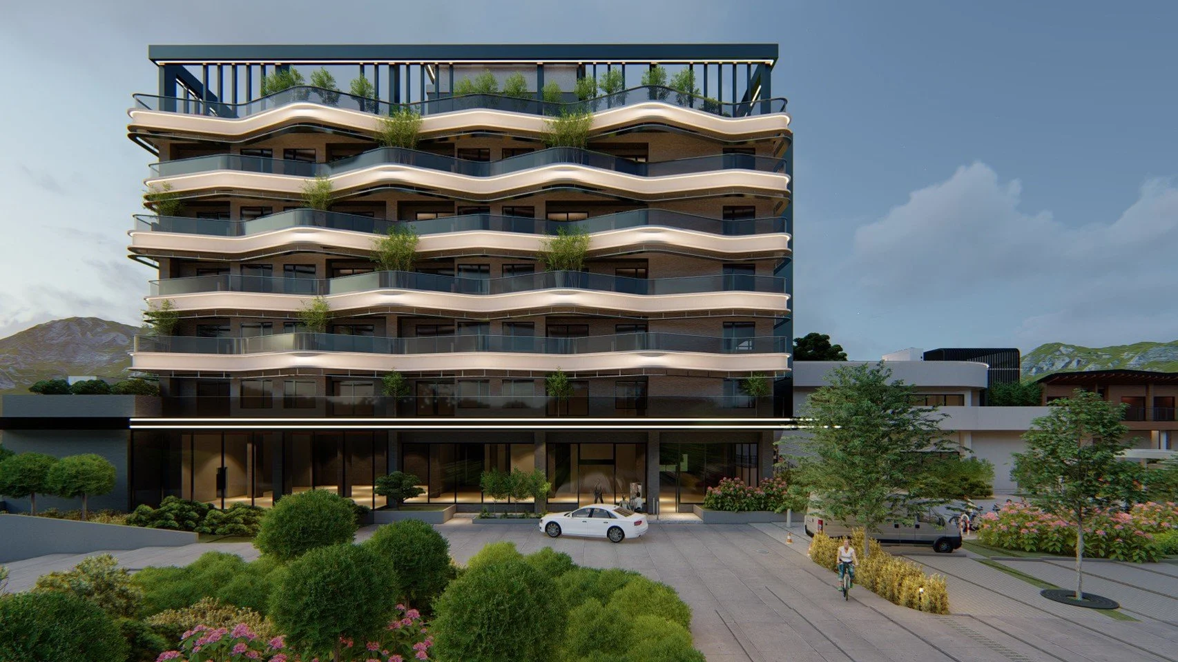 Modern multi-story residential building with winding balconies decorated with greenery, surrounded by landscaped greenery and trees, with cars and people in front, against a backdrop of mountains and a partly cloudy sky.