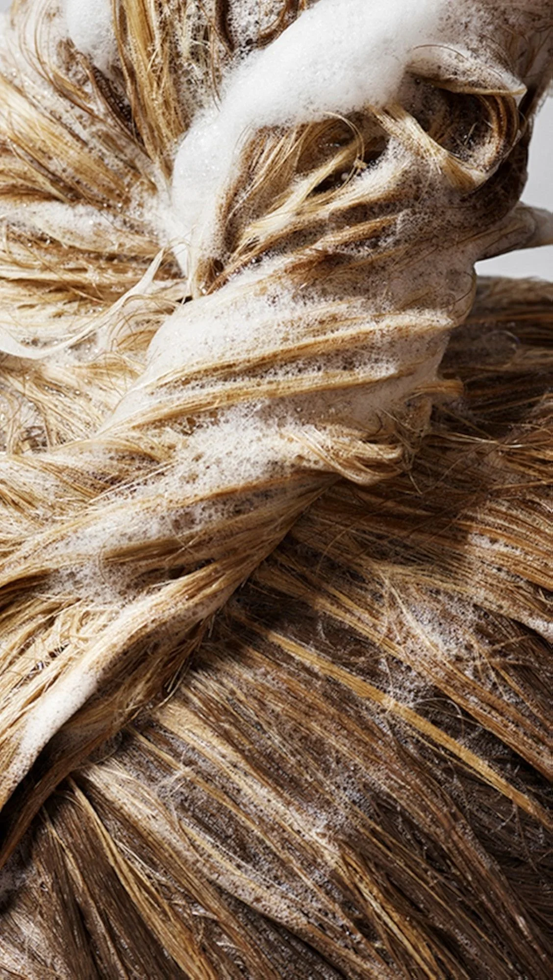 Close-up of a wet, braided natural fiber rug with soap suds on its surface.