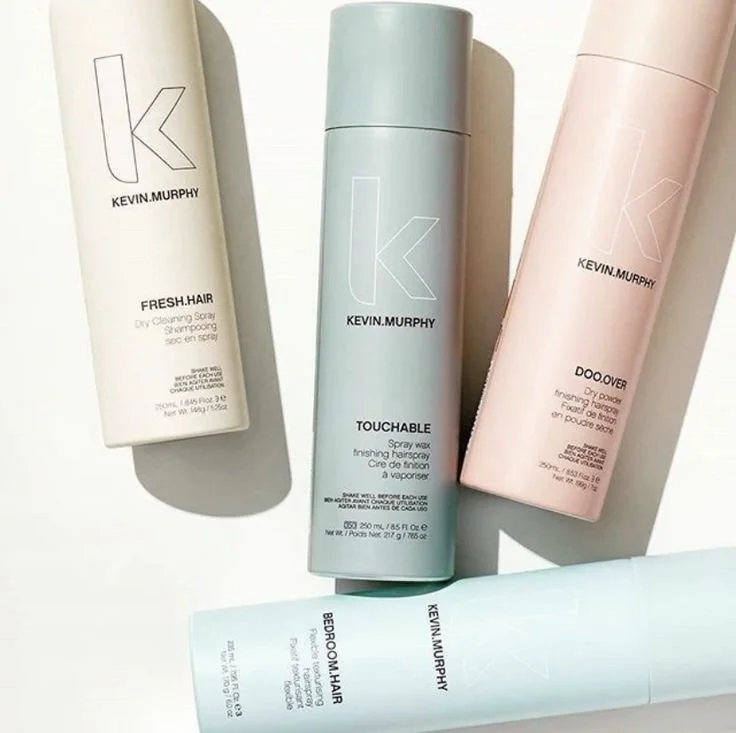 Four KEVIN.MURPHY hair care products in pastel-colored bottles, including Fresh.Hair, Touchable, Doo.Over, and Bedroom.Hair, placed on a white surface with shadows.