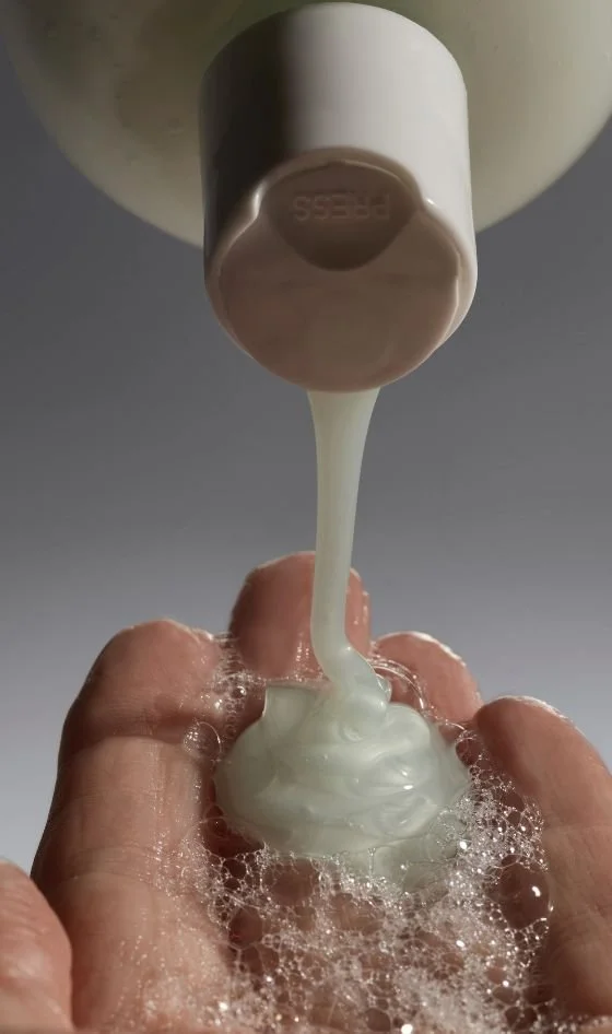 Pouring shampoo or liquid soap into a person's hand with lather and bubbles.