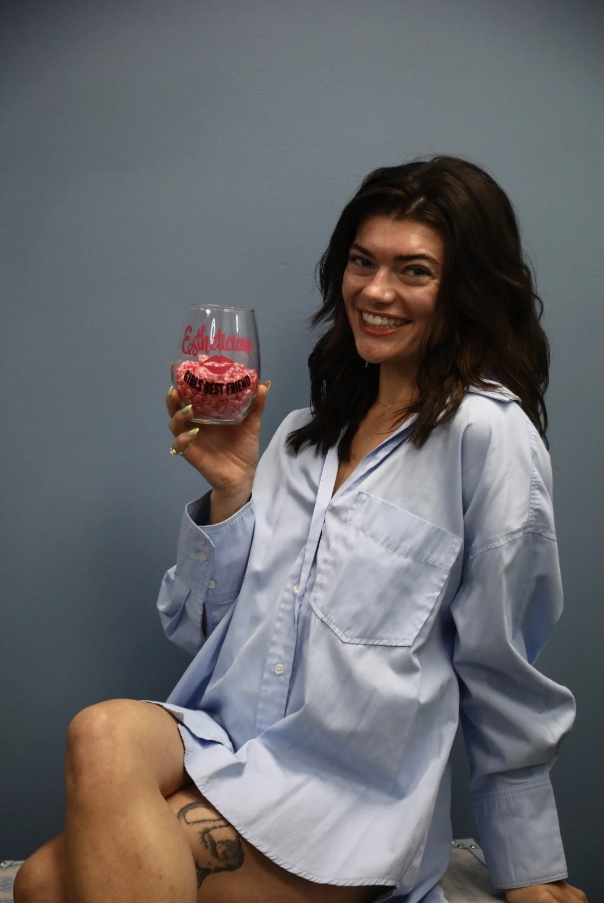 waxer holding esthetician wine glass filled with pink wax beads