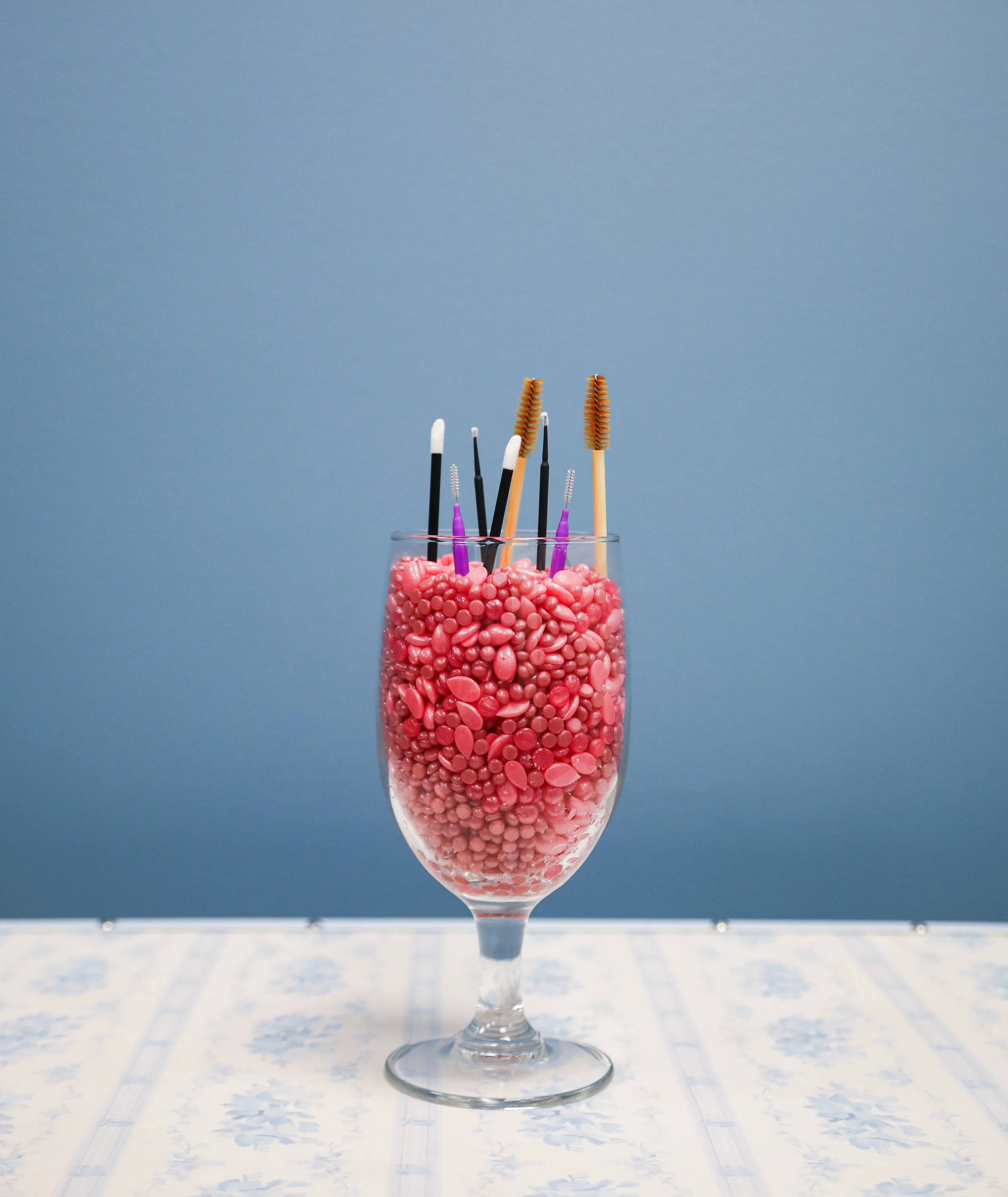 wax beads in wine glass with lip brushes, spoolies, dental brisltes