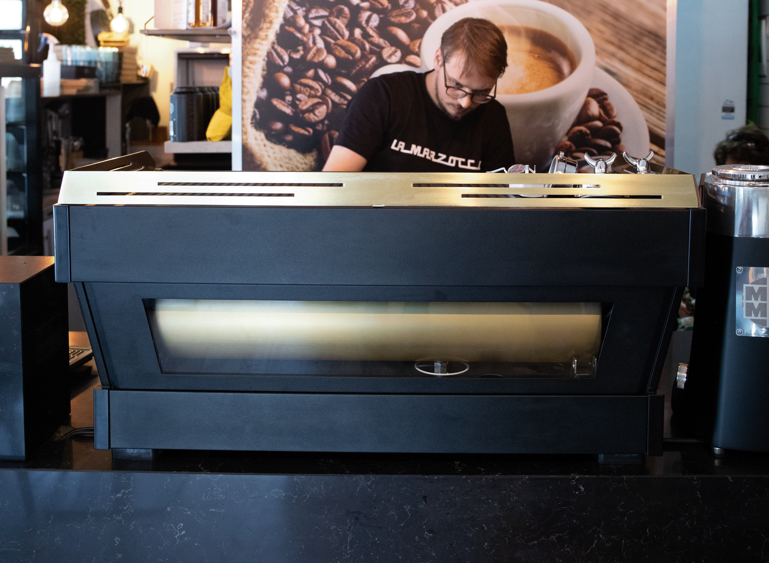Barista preparing espresso behind a coffee machine at a coffee shop.