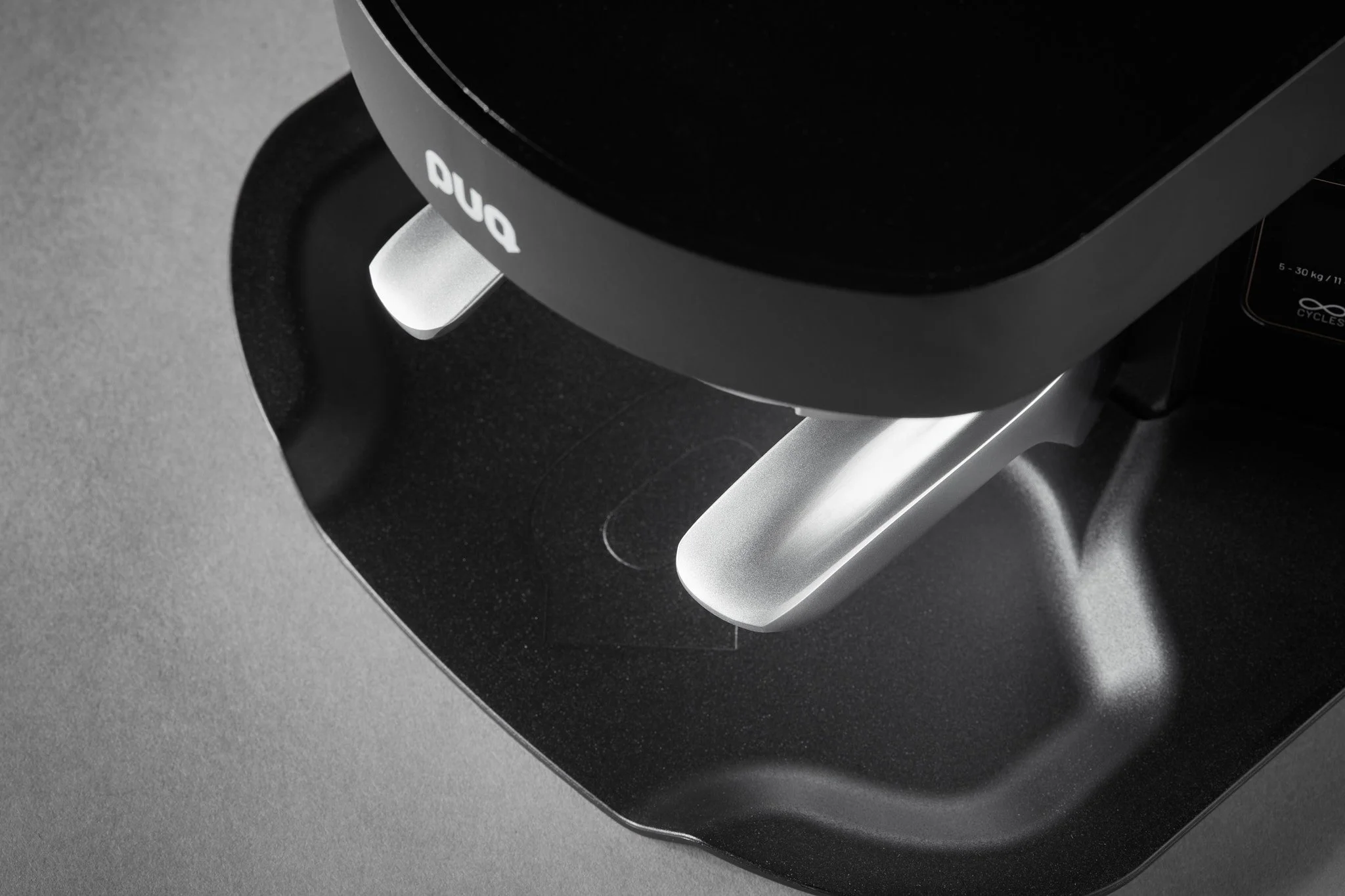 Close-up of a black and silver mechanical device with the brand name 'Duo' on it, resting on a dark surface.