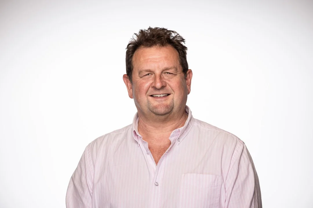 Stuart, founder and principal consultant at Searchlight - New Zealand's leading Business network consulting, man with short, brown hair, smiling and wearing a button-up shirt against a plain white background.