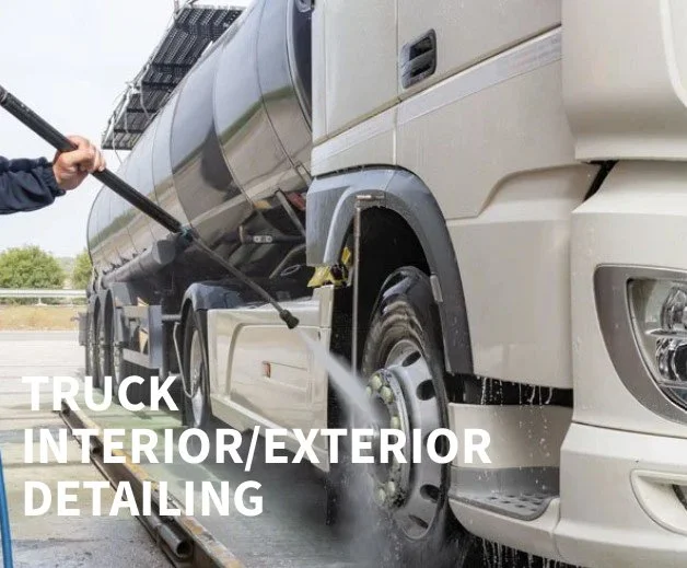 Person pressure washing the exterior of a large semi-truck during truck interior/exterior detailing.