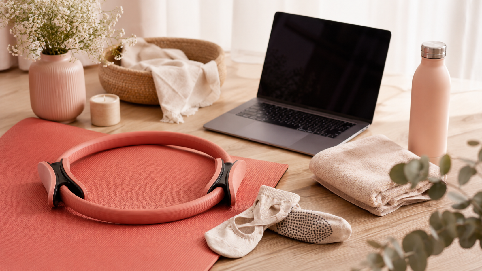 Virtual Pilates setup with mat, Pilates ring, laptop, grip socks, towel, and water bottle