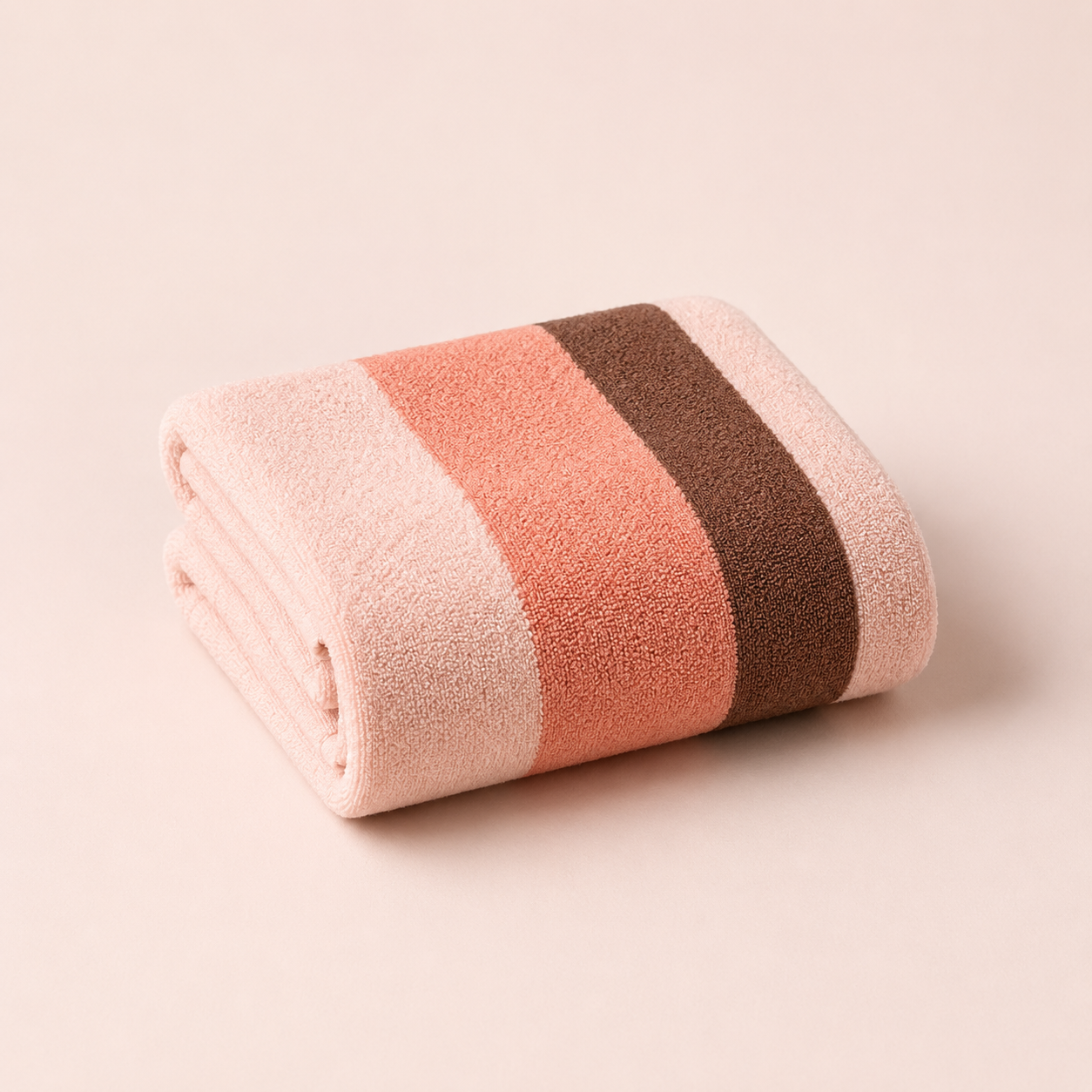 A neatly folded towel with pink, peach, and brown horizontal stripes on a plain light background.