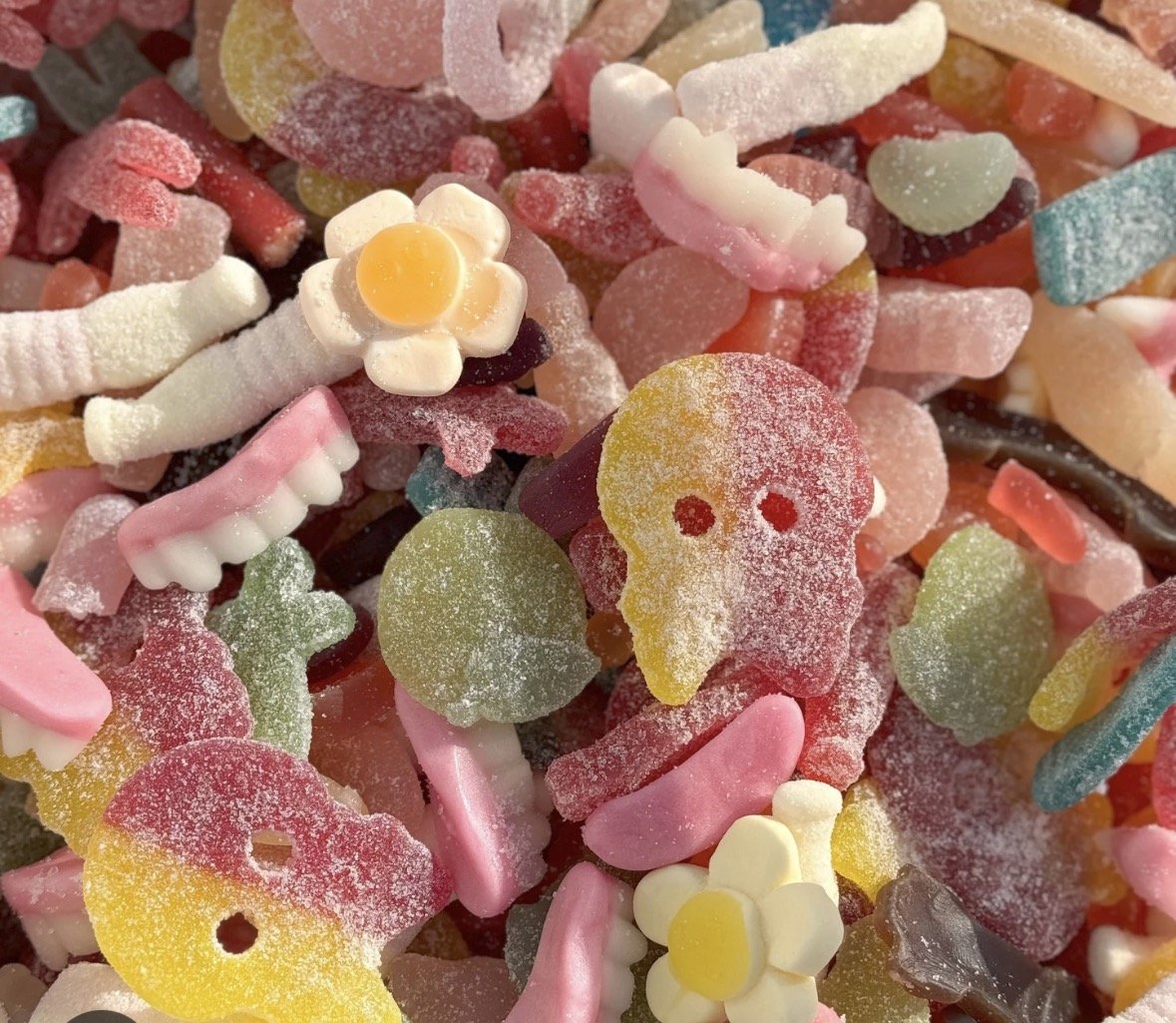 Close-up of assorted colorful gummy candies shaped like flowers, skulls, and animals, coated in sugar.