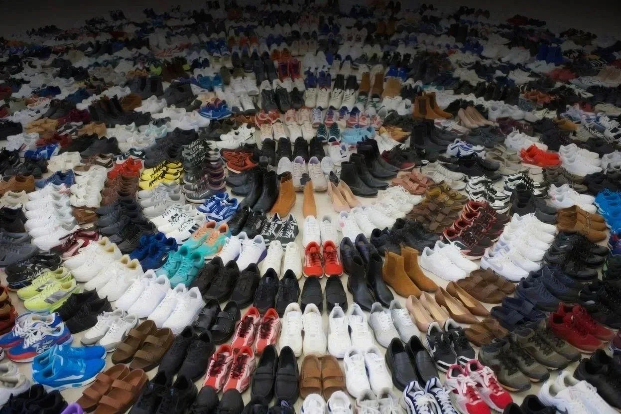 A large collection of various shoes arranged in concentric circles on the floor.