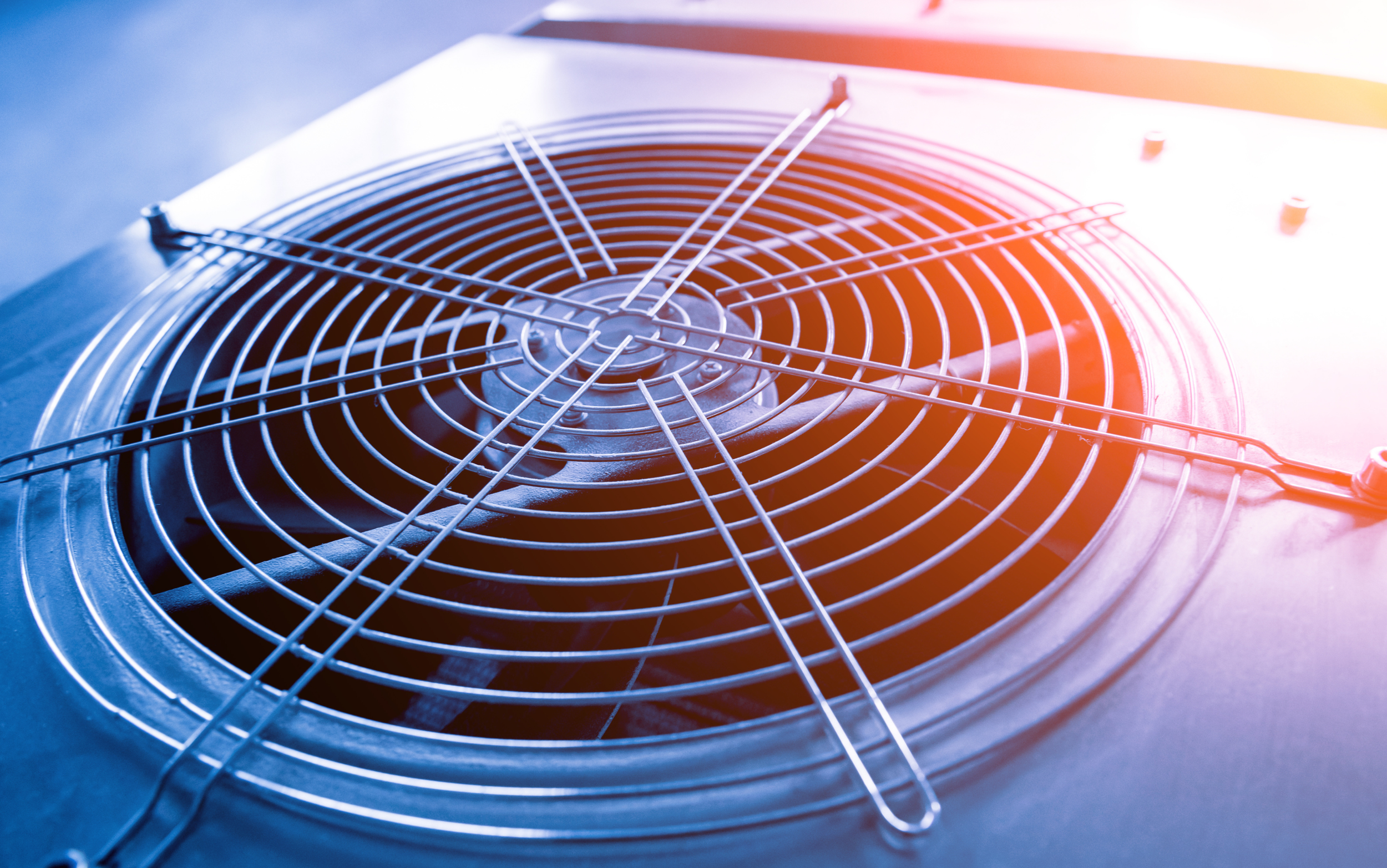 A close-up view of an electric stove's fan cover with metal grid and blades beneath it.