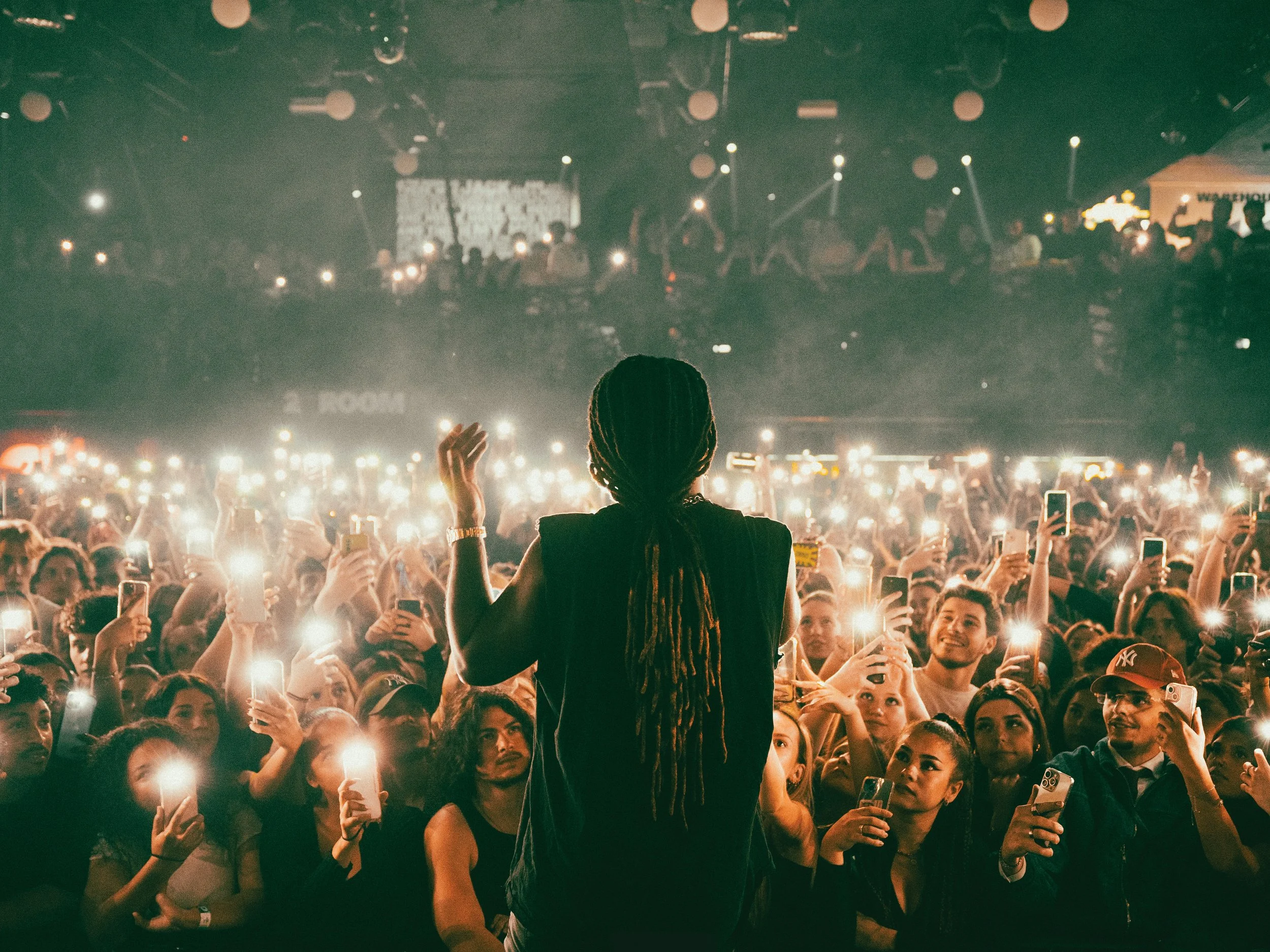 Artist performing in front of a crowd with their phones out