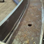 Close-up of a boat hull in a workshop with a hole in the hull's surface.