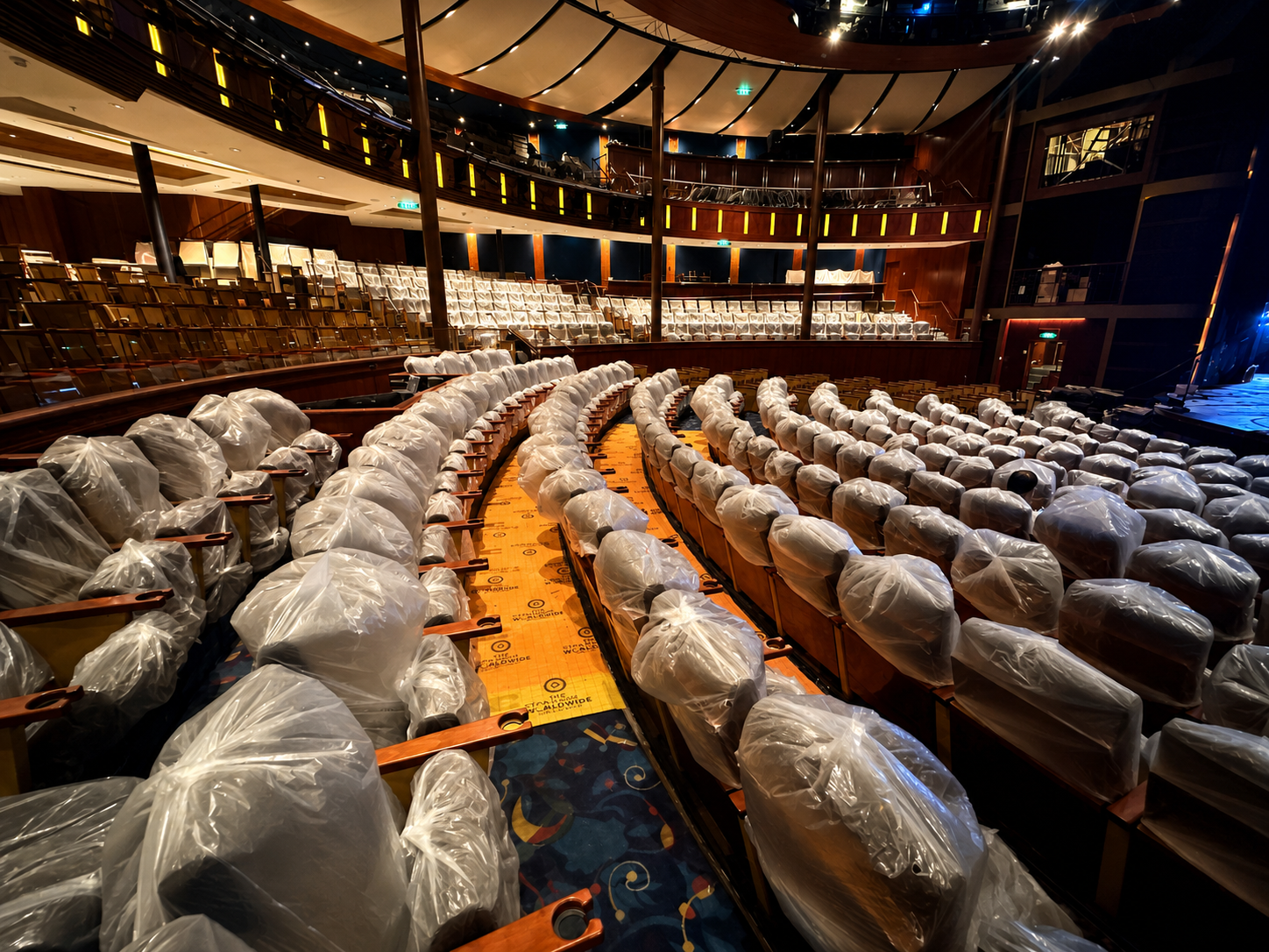 An empty theater or auditorium with seats covered in protective plastic, ready for a performance or event.