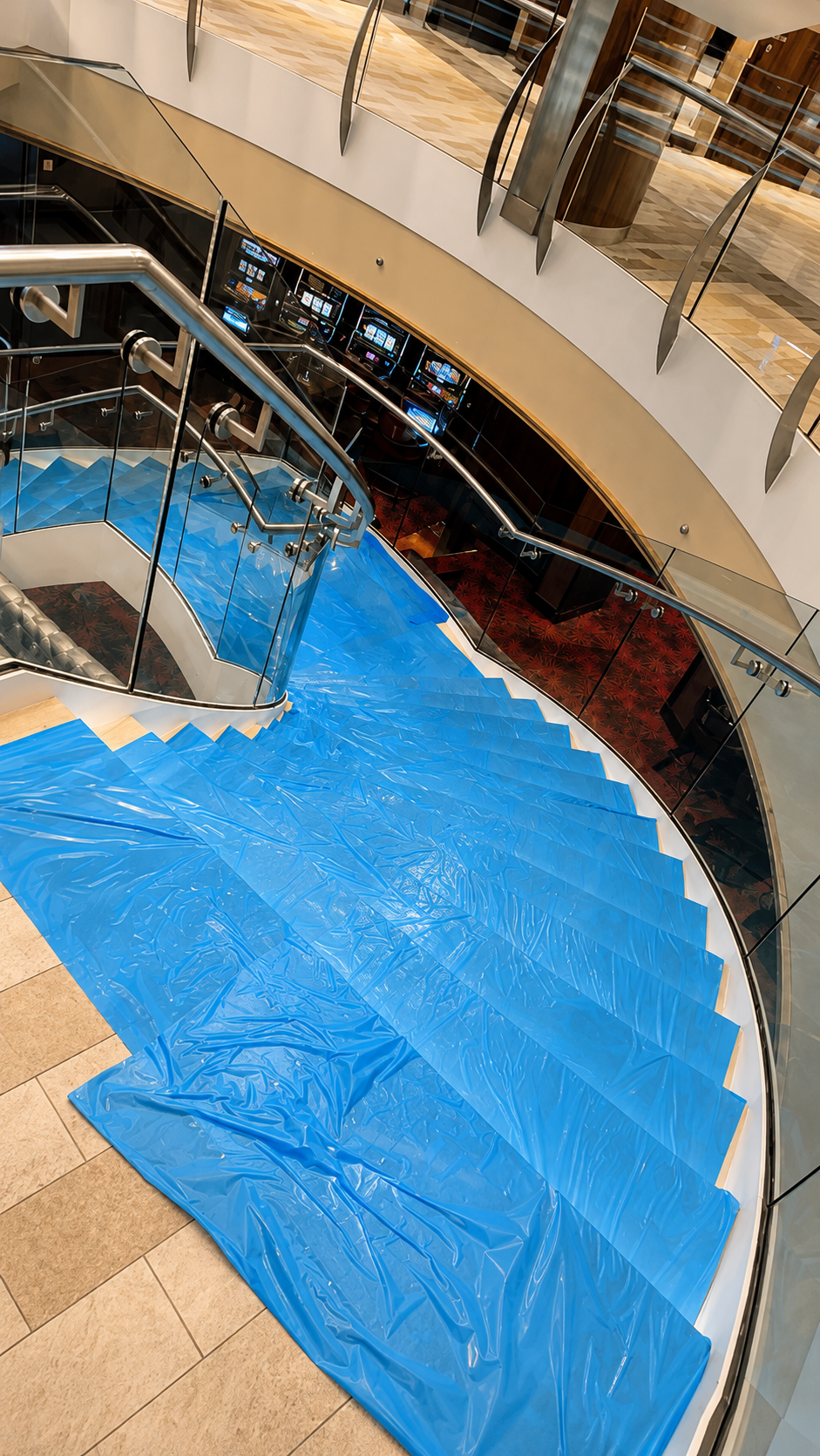Blue plastic sheet covering a staircase in a shopping mall, with escalators visible in the background.