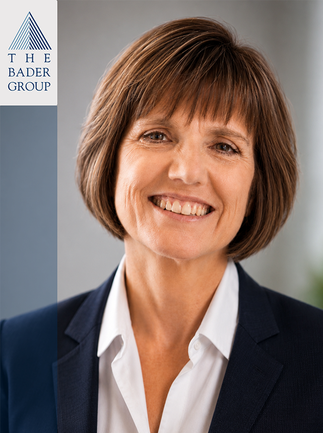 professional woman with short brown hair smiling, wearing a white shirt and dark blazer, in an office setting with The Bader Group logo on the left.