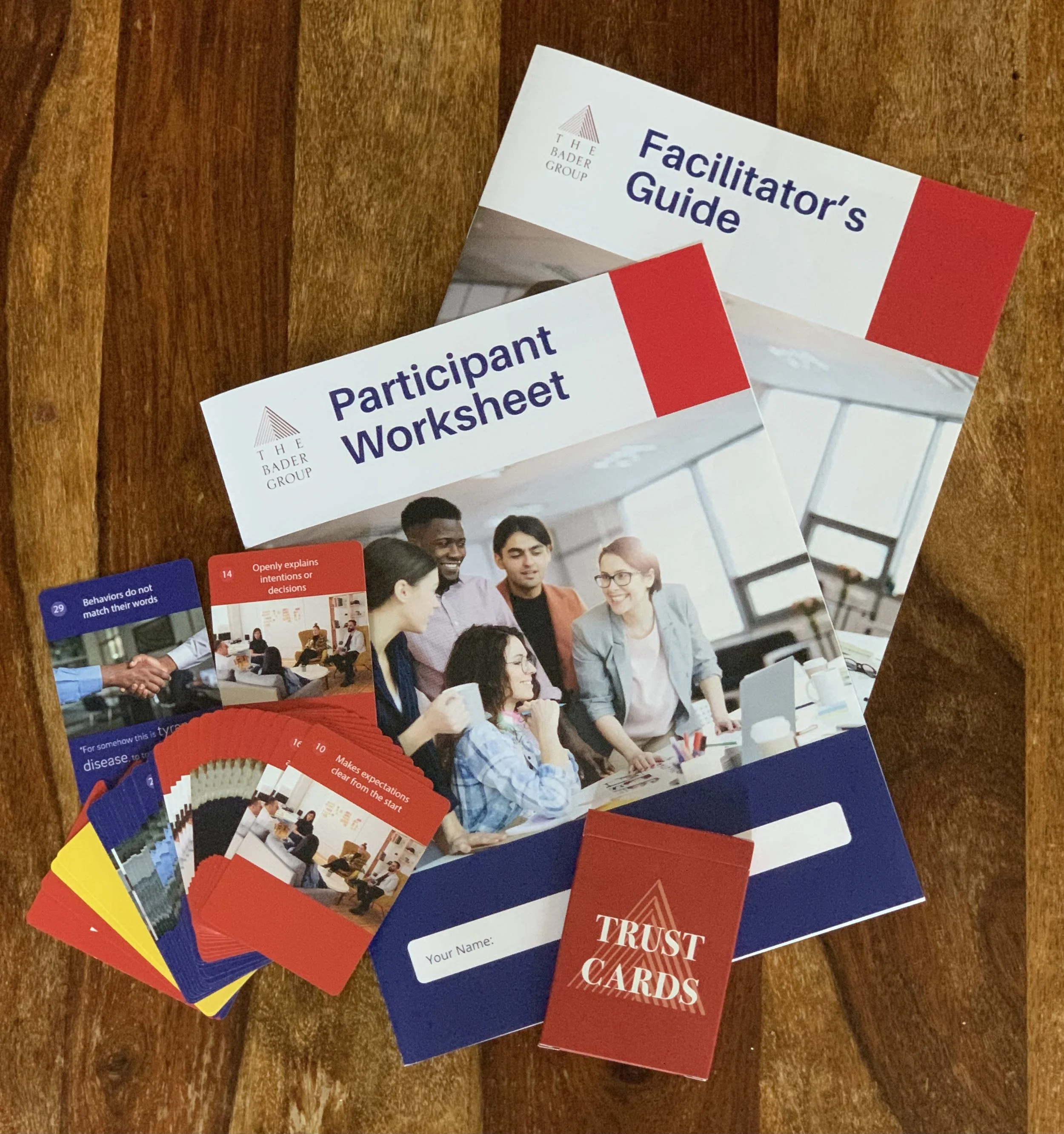 A collection of trust cards, facilitator's guide, and participant worksheet on a wooden surface, used for group activities.