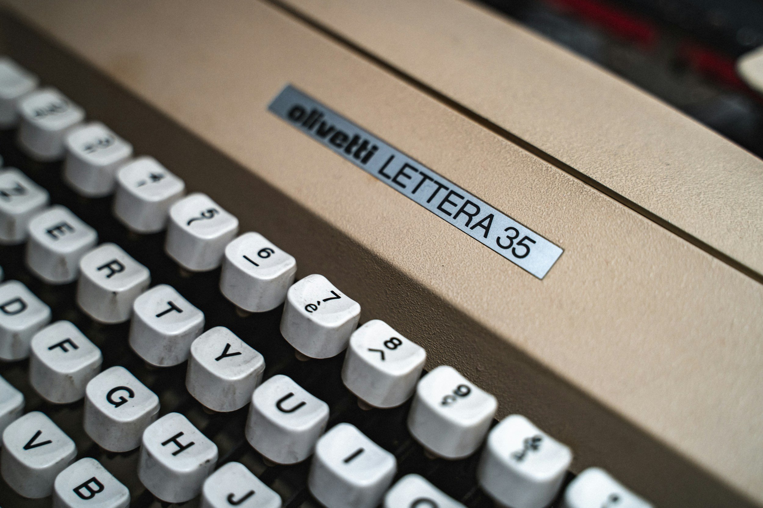 Close-up of a vintage Olivetti Lettera 35 typewriter showing white keys with black lettering and a beige metal body with a label indicating the model name.
