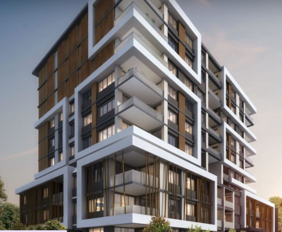 Modern multi-story residential building with white and brown facades, large glass windows, and balconies, set against a partly cloudy sky.