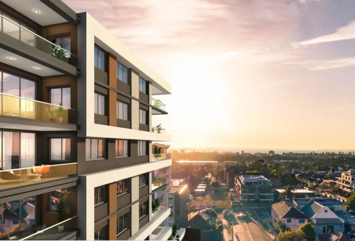 Modern multi-story apartment building with balconies during sunset over a suburban neighborhood.