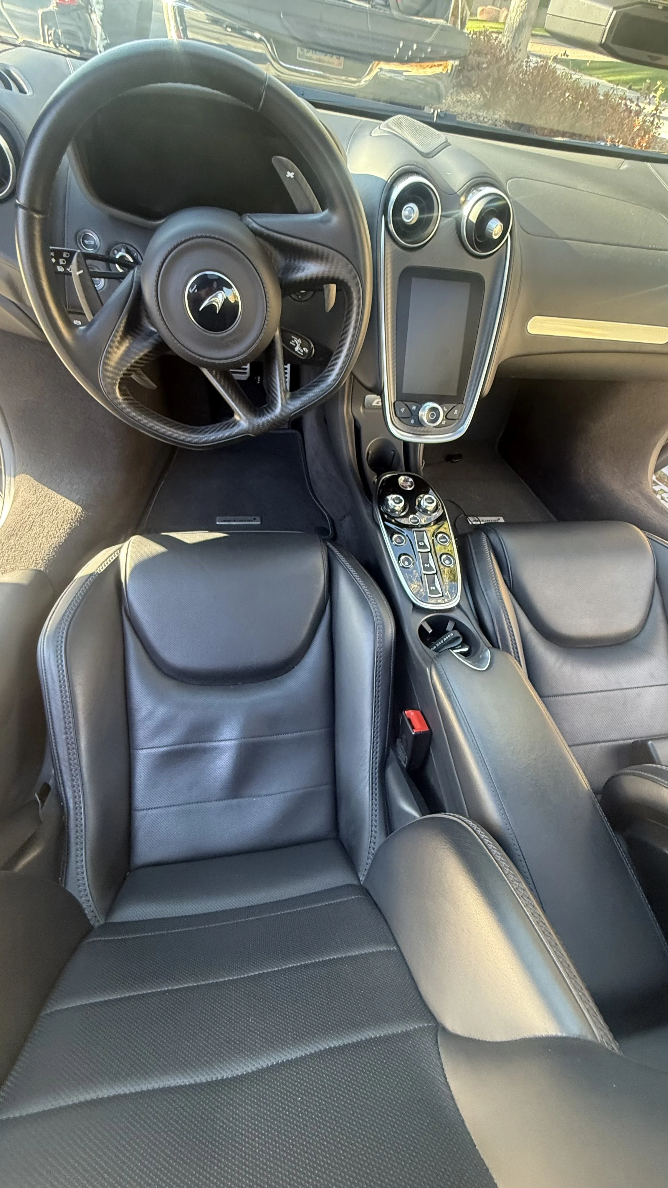 Interior of a luxury sports car with black leather seats, a steering wheel with a cheetah logo, a large touchscreen display, and control panels with various buttons.