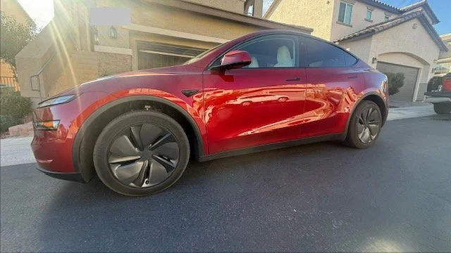A ceramic coated red Tesla Model 3 sedan parked on a residential street in front of houses. Ceramic coatings Las Vegas