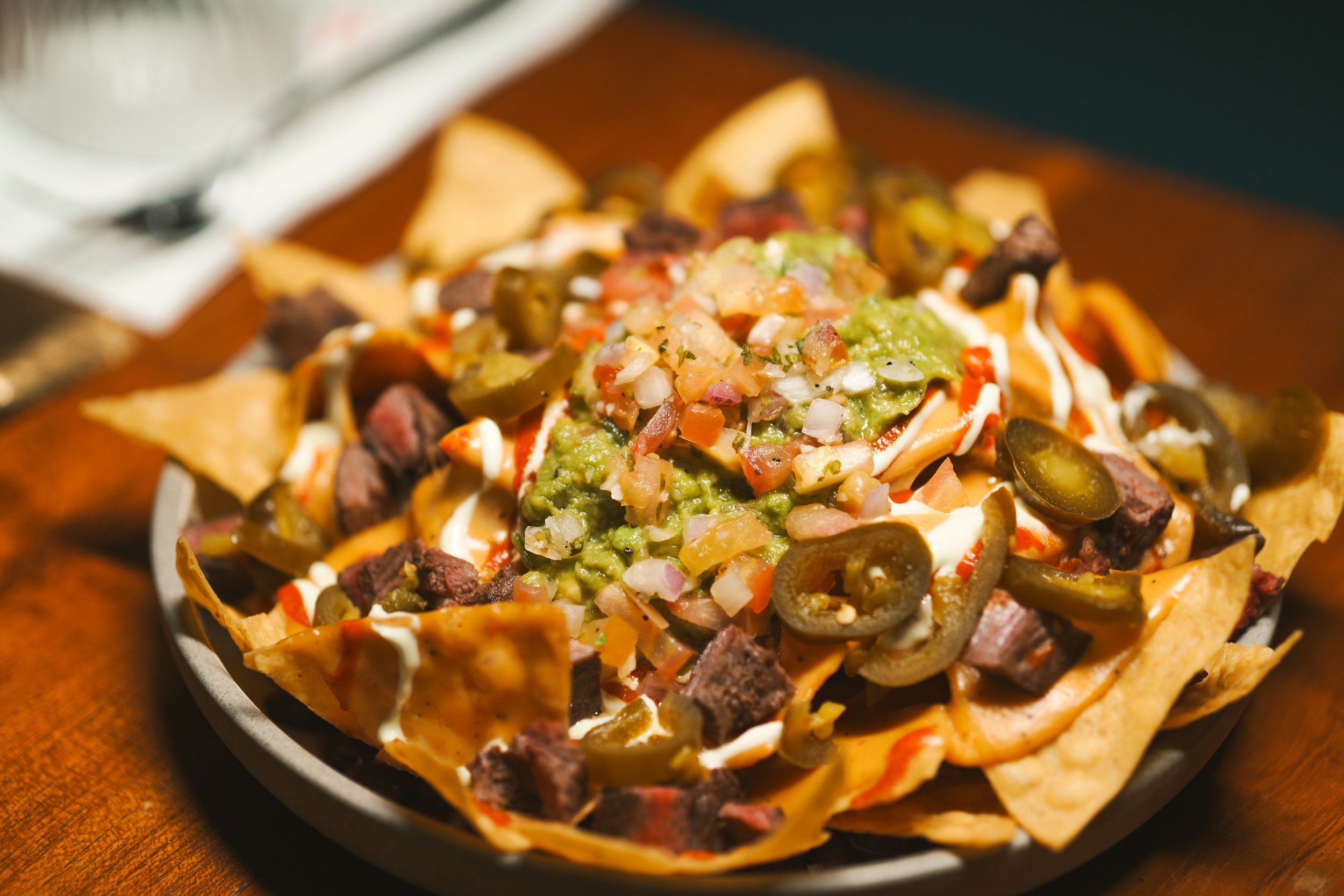 Nacho Mama's Nachos at Vatos, loaded with queso, black beans, guacamole, and pico de gallo