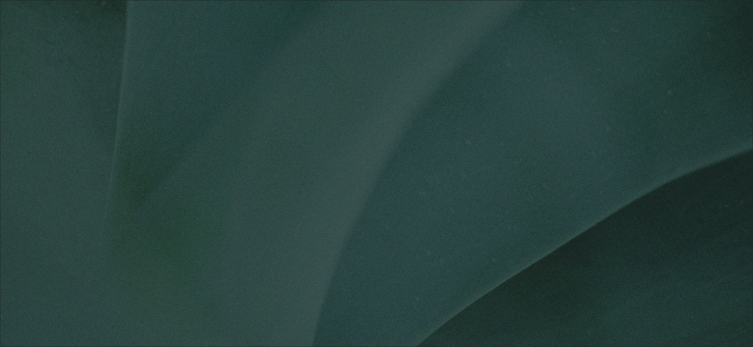 Close-up of a teal-colored ceiling and wall with a subtle shadow and light reflection.